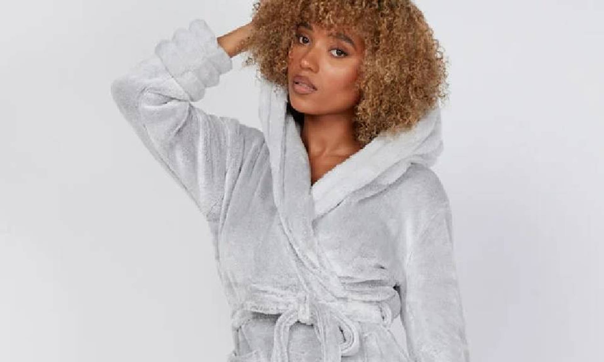  A woman wearing a grey, fluffy dressing gown from Boux Avenue. 