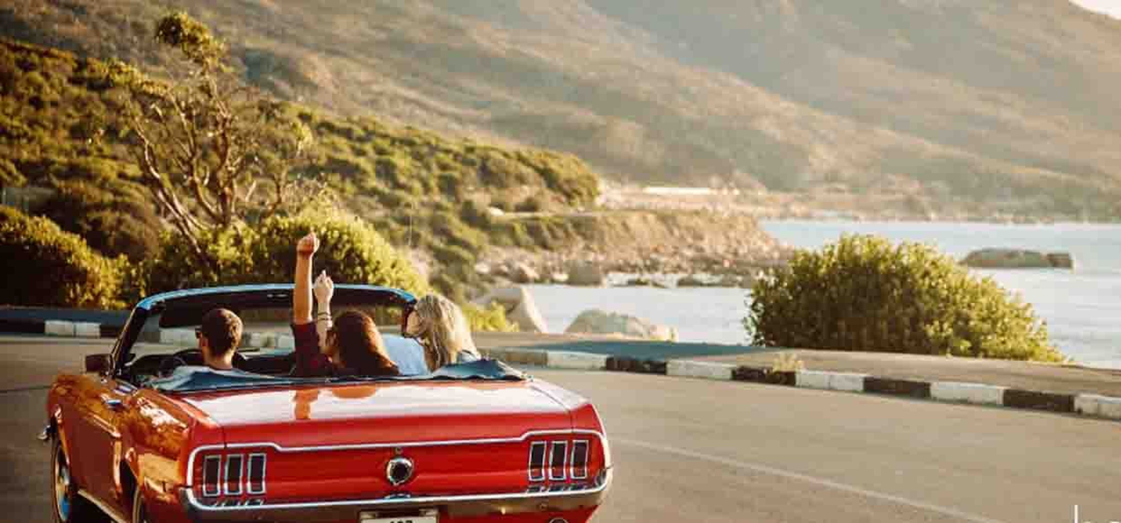 people in a red car driving on a windy road