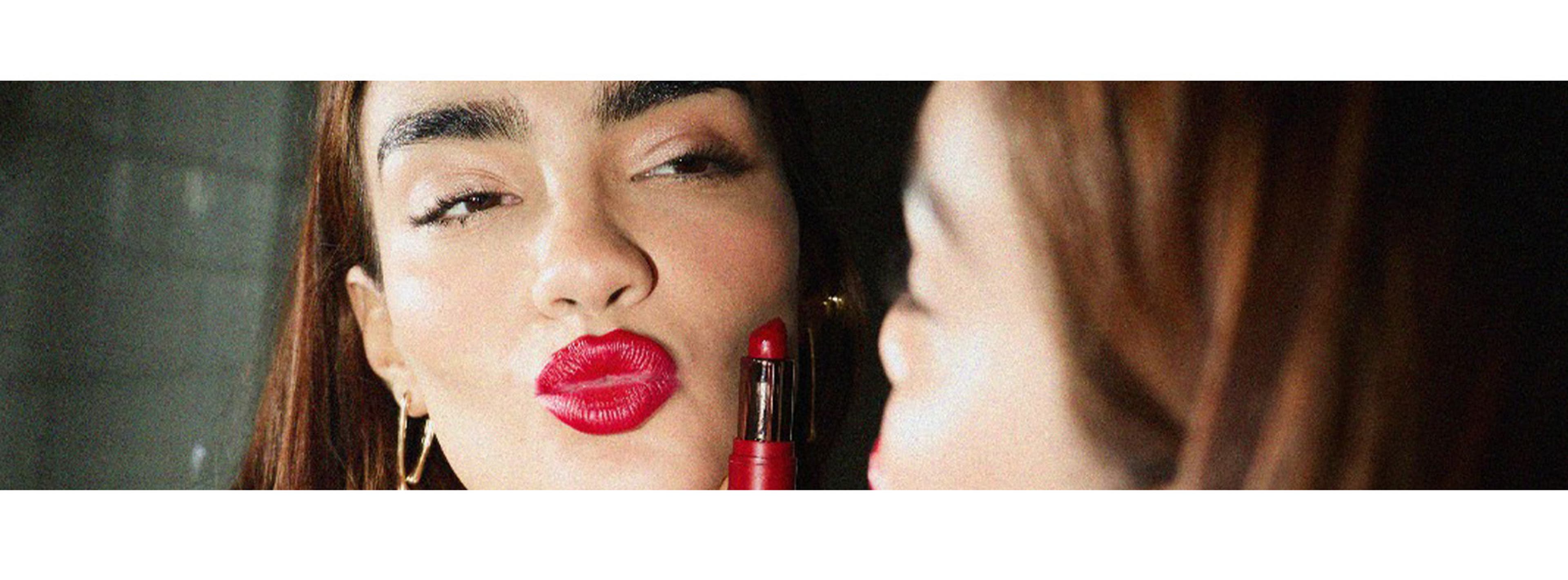 Woman pouting in mirror with red lipstick