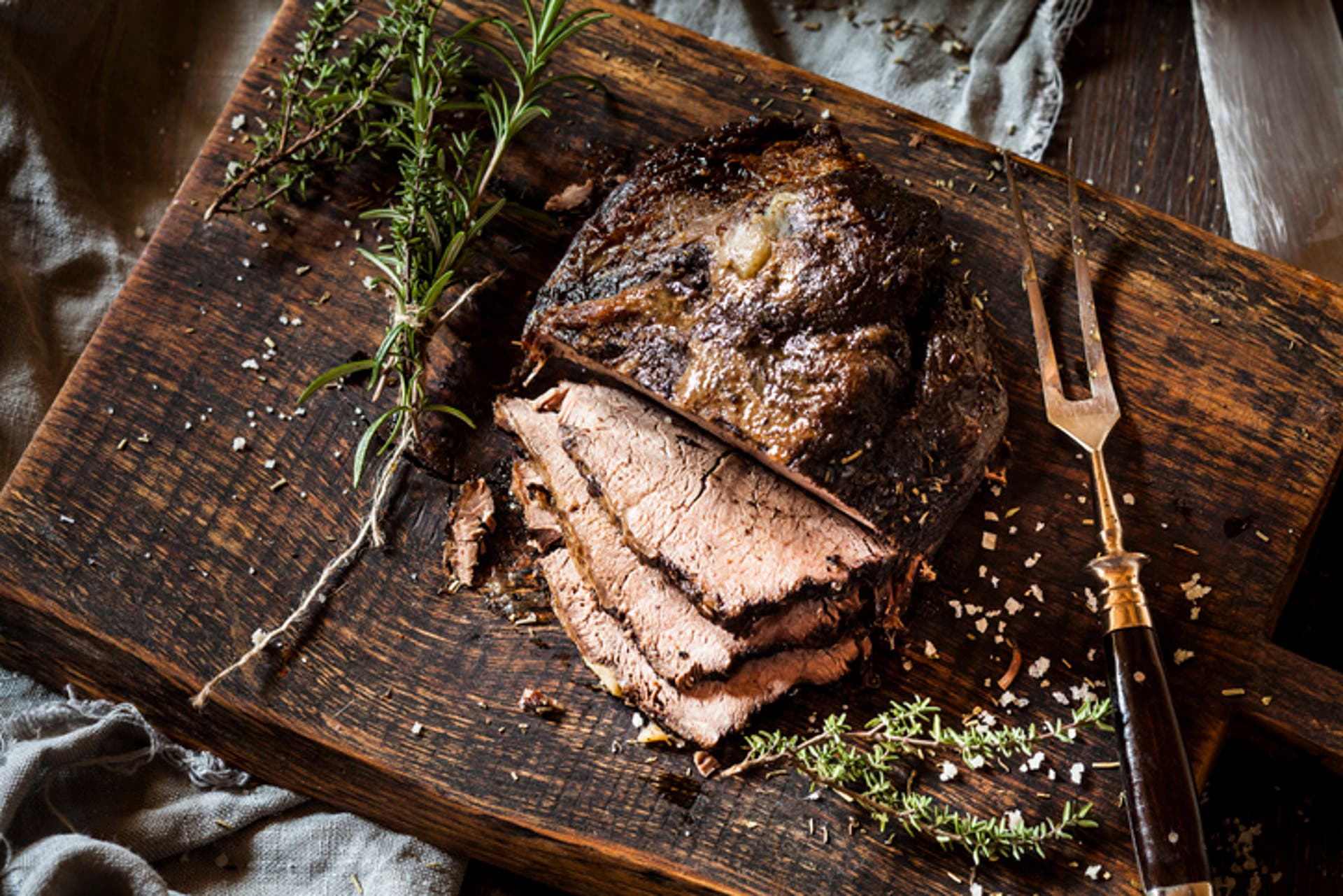  Sliced roast beef, rosemary, thyme and sea salt on chopping board 