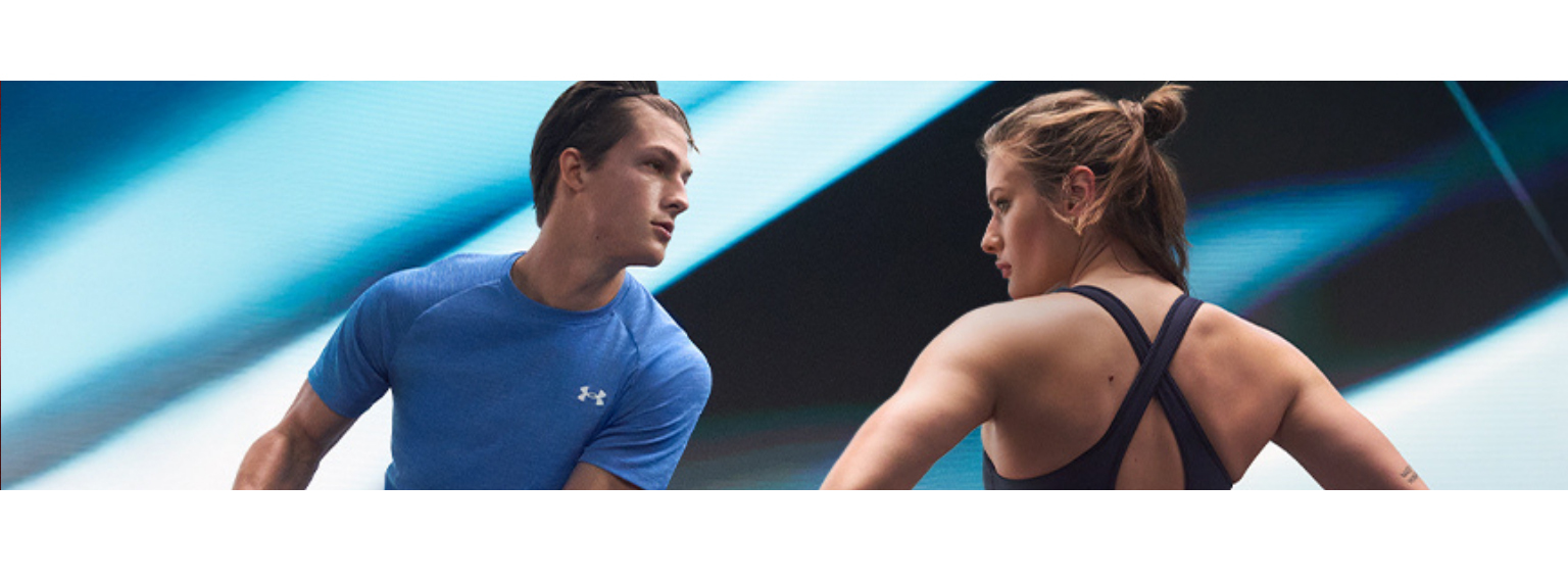  Man and Woman modelling Under Armour's athleisure wear with the man wearing a blue tshirt holding a ball and the woman wearing the brand's sport's bra 