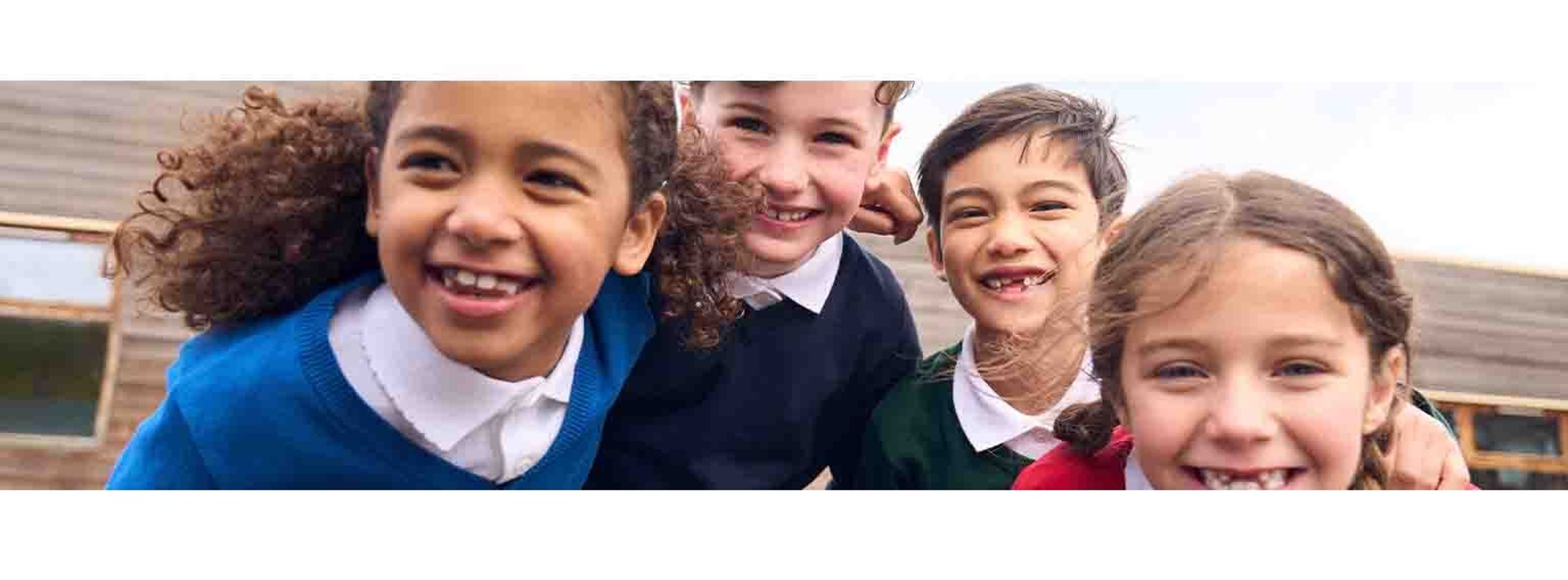 bunch of kids smiling closely at the camera in their uniform