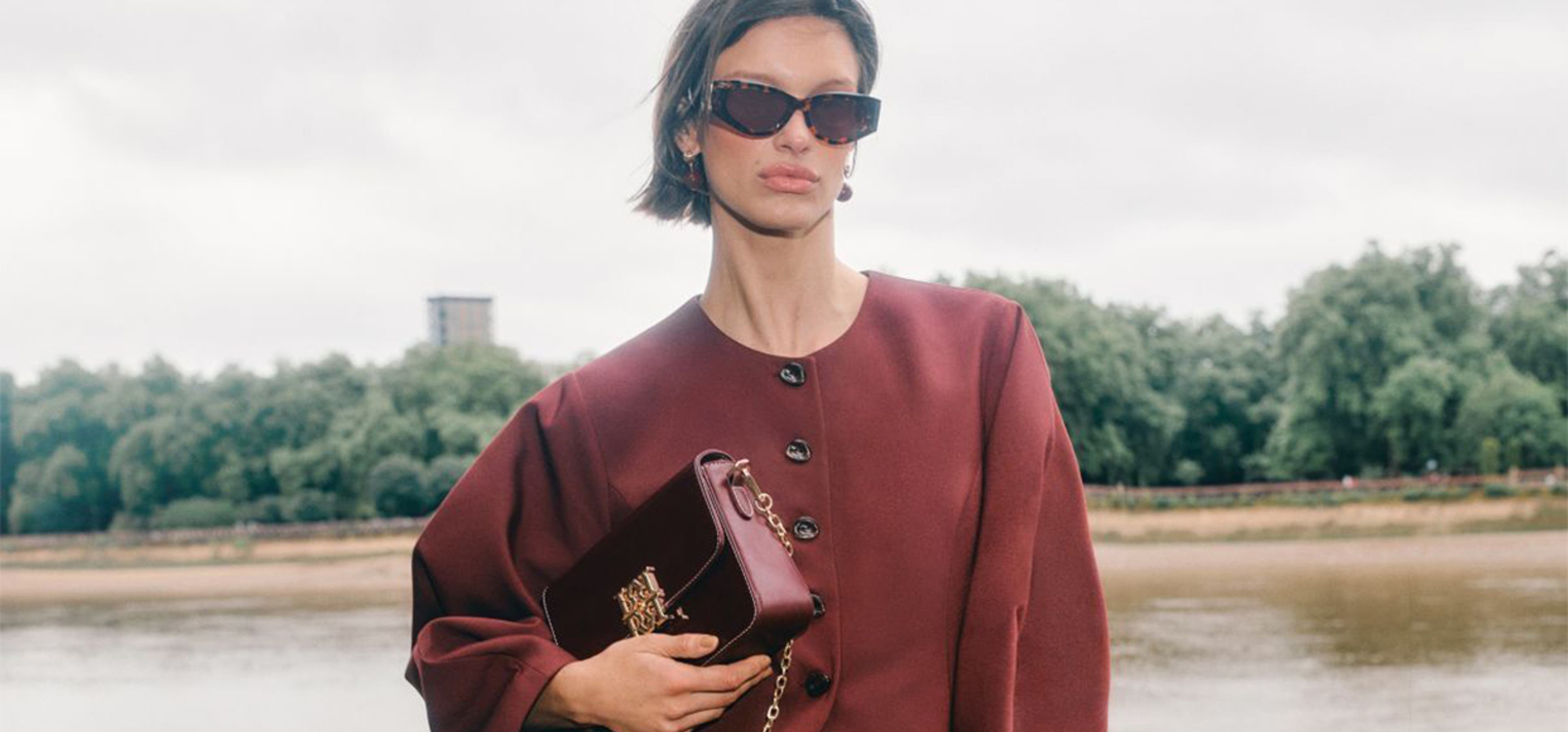 Women posing in centre frame in burgundy red two piece blazer set with sunglasses on