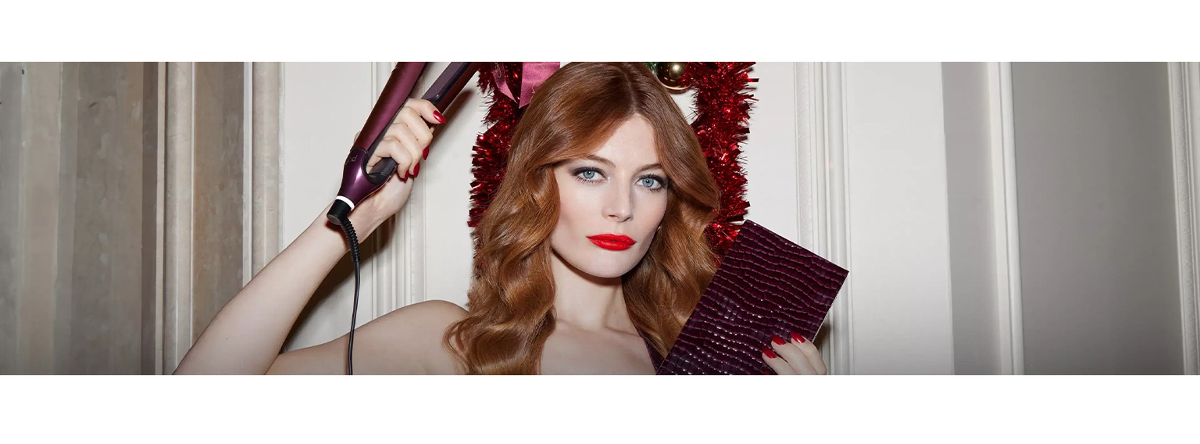 ginger woman holding straigheners with christmas decorations