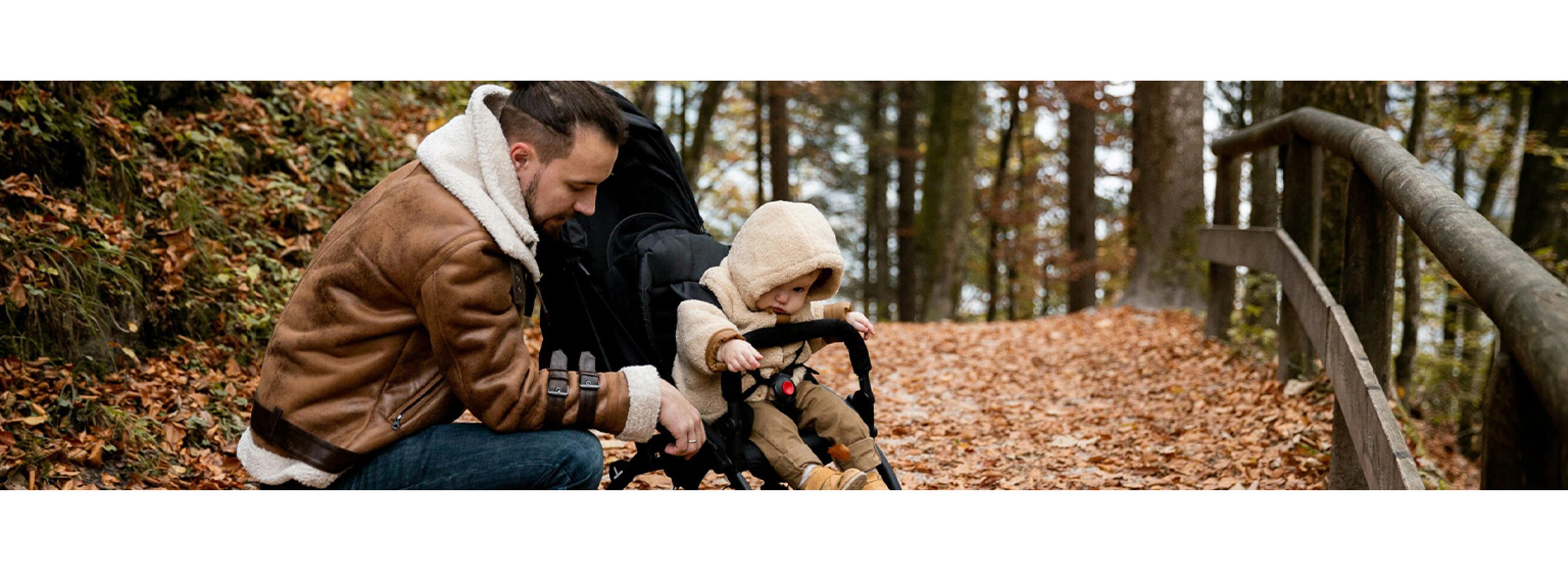 dad and baby in stroller in an autumn forest
