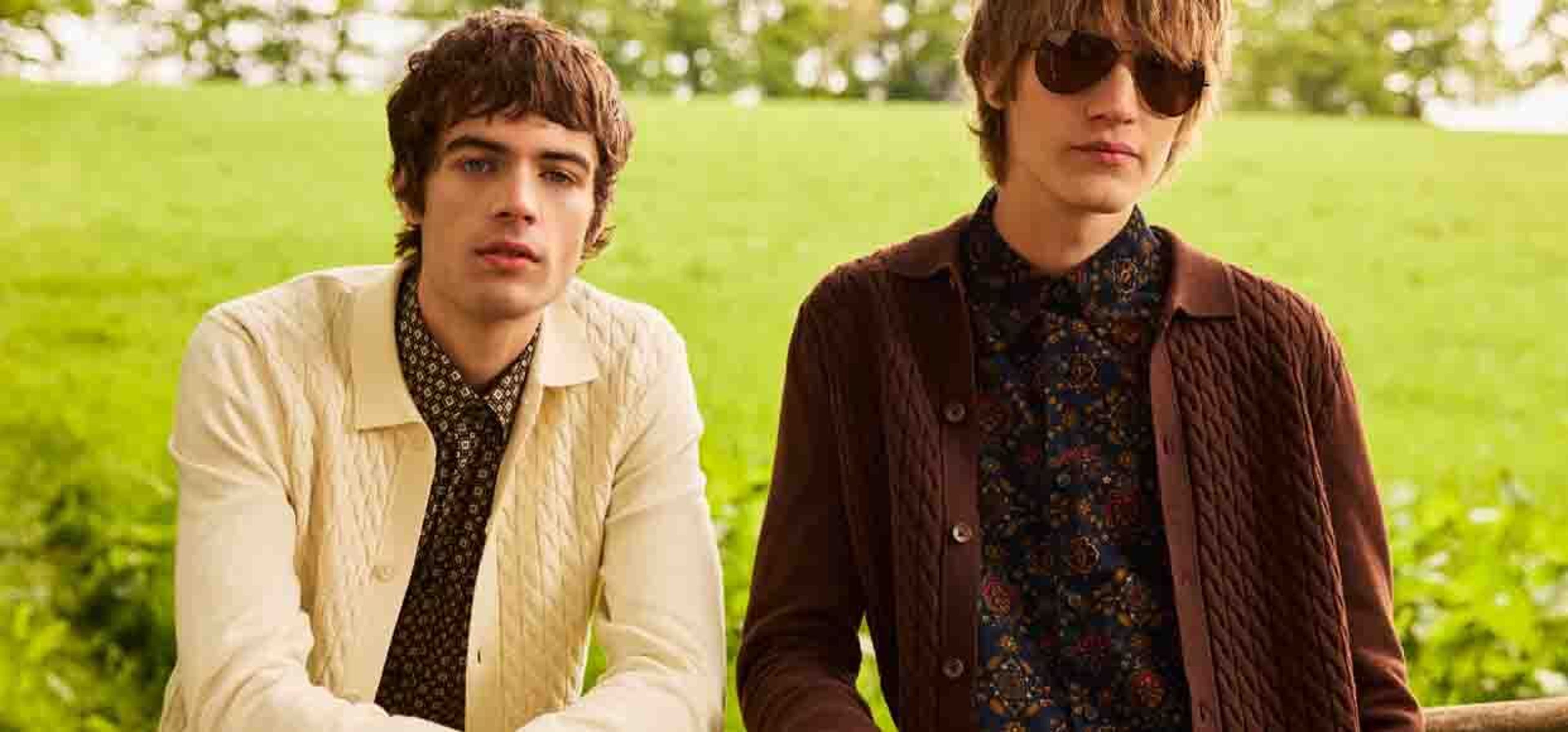 Two boys with long haircuts posing in a field