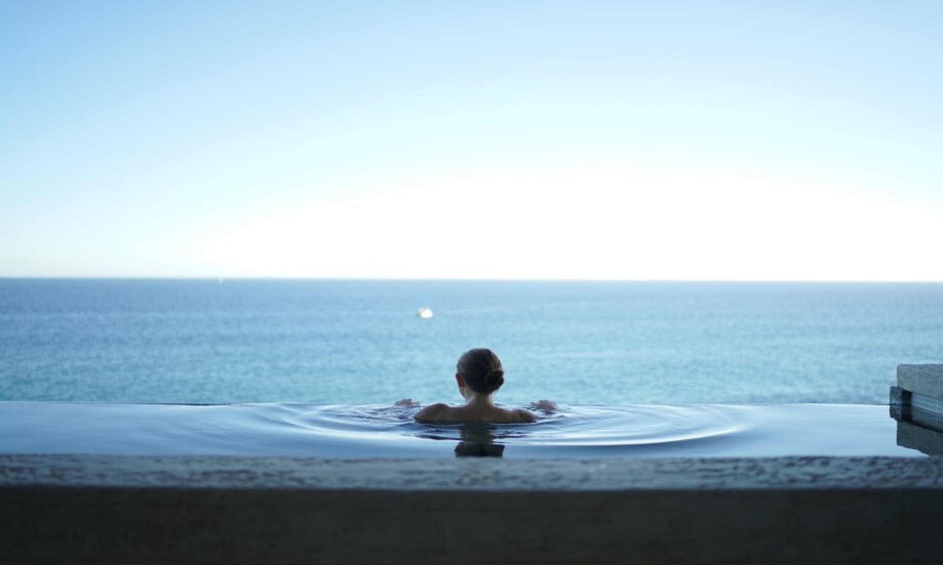  Image of a woman in an infinity pool, overlooking a sea view 