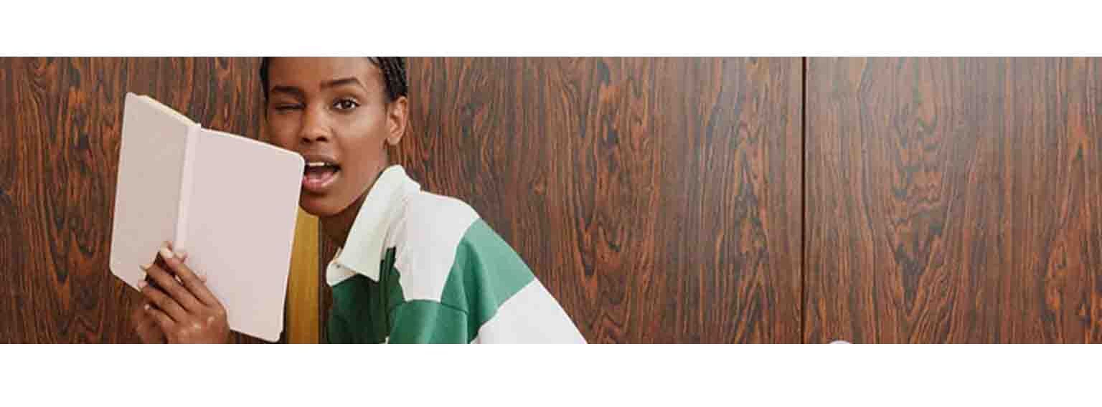 woman with with strip shirt posing winky with a book in hand