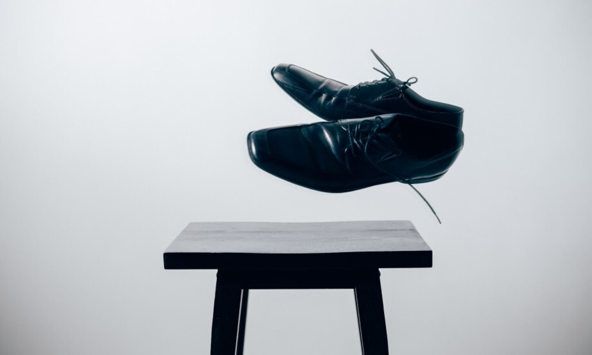  A pair of smart, black shoes artistically floating above a stool 