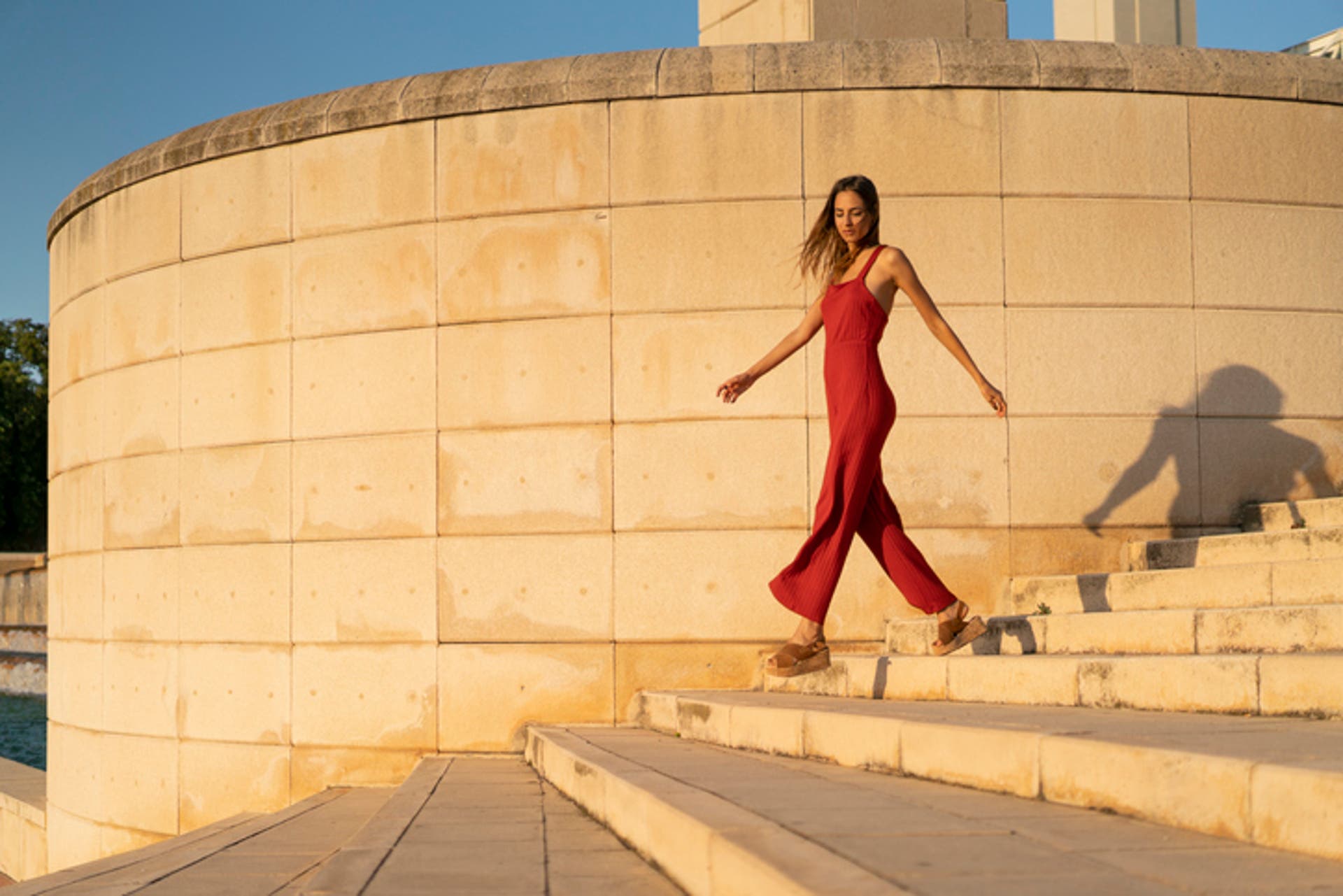  young woman wearing red jumpsuit walking on stairs 