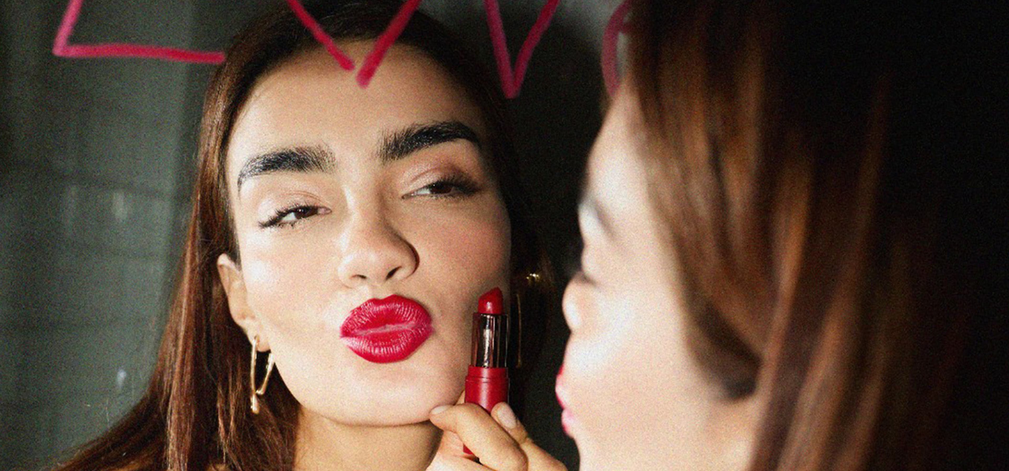 Woman pouting in mirror with red lipstick