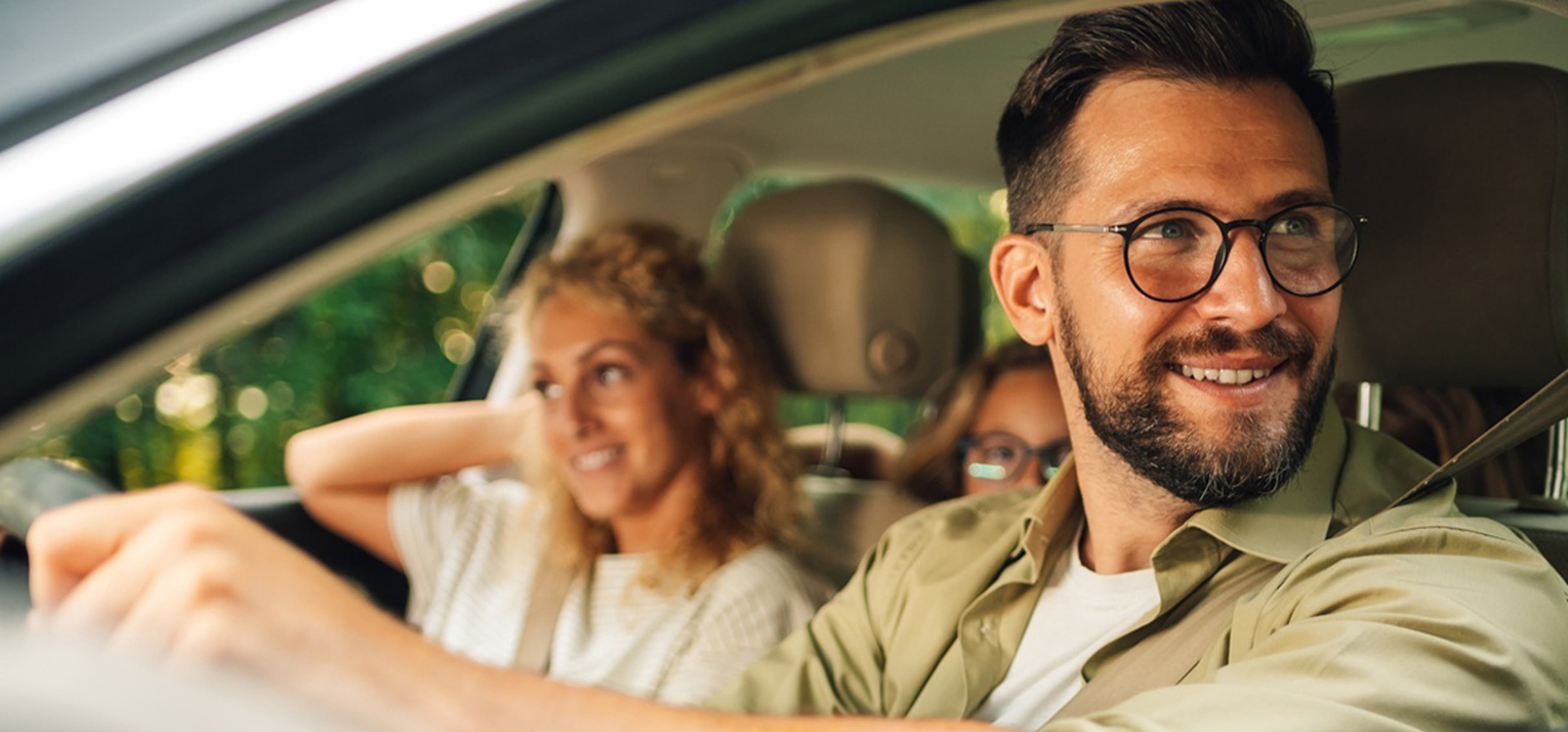 Dad driving car with mom in passenger seat and kids in the backseat during their vacation