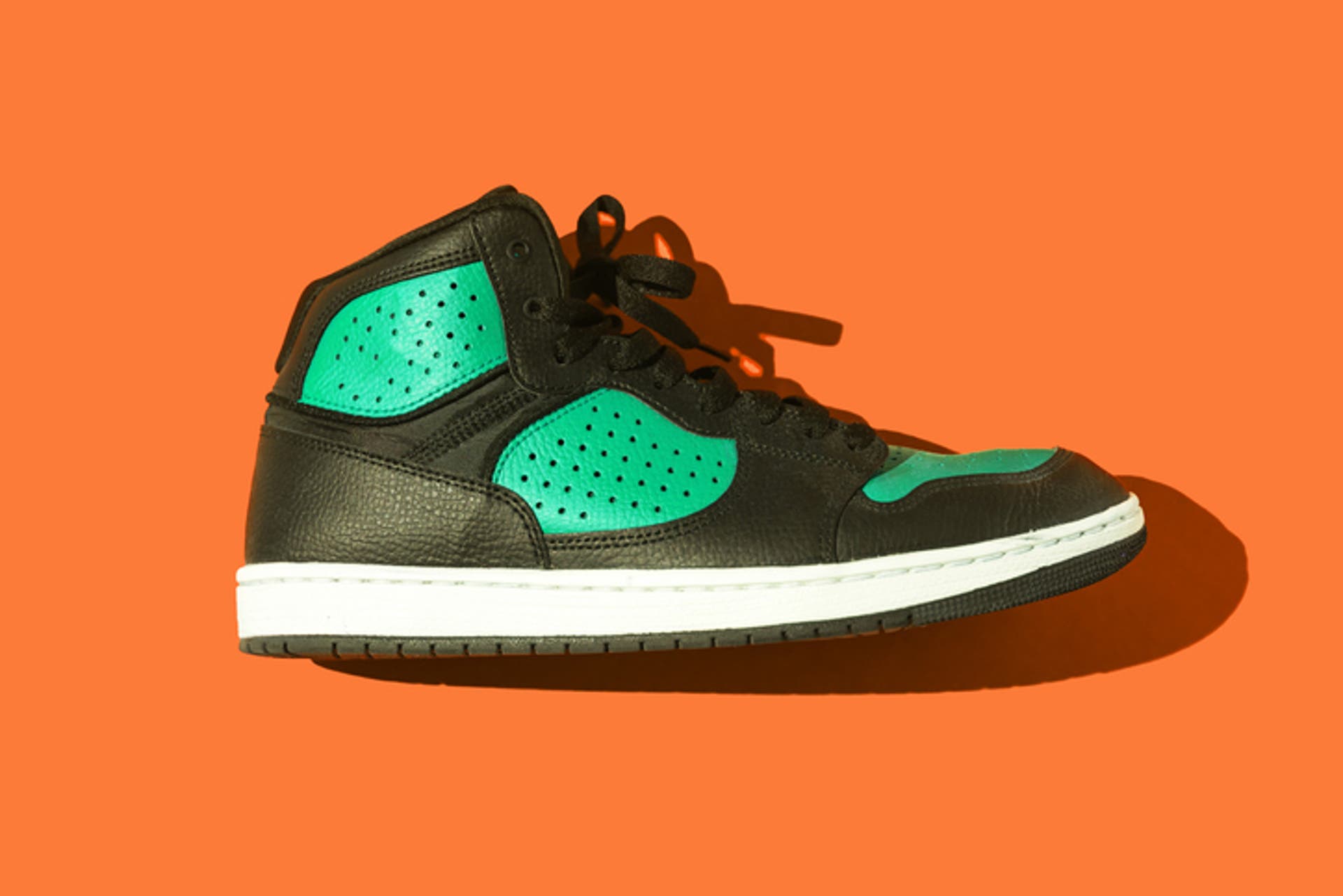  Black and green basketball sneakers, on a orange background 