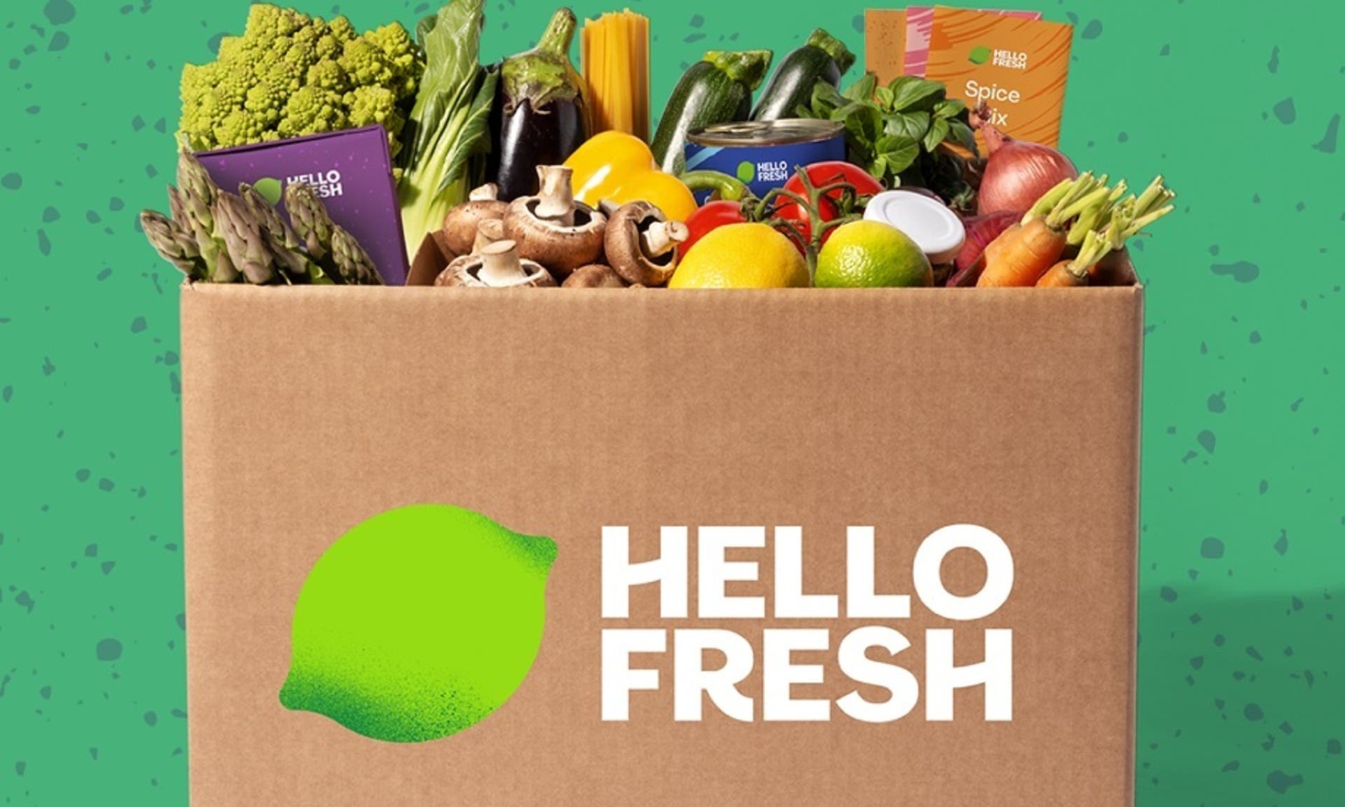  A photo of a Hello Fresh cardboard box containing a selection of fresh fruit and vegetables against a green background. 