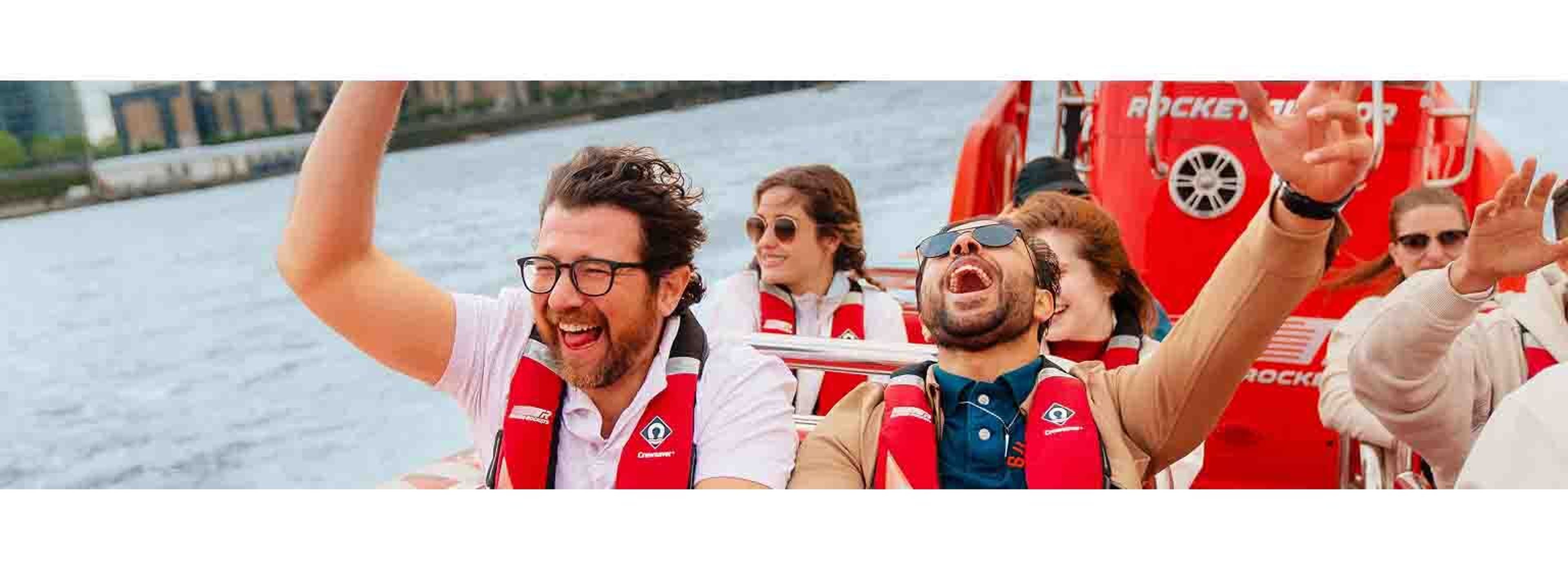 two people in life jackets on a speed boat, smiling happy
