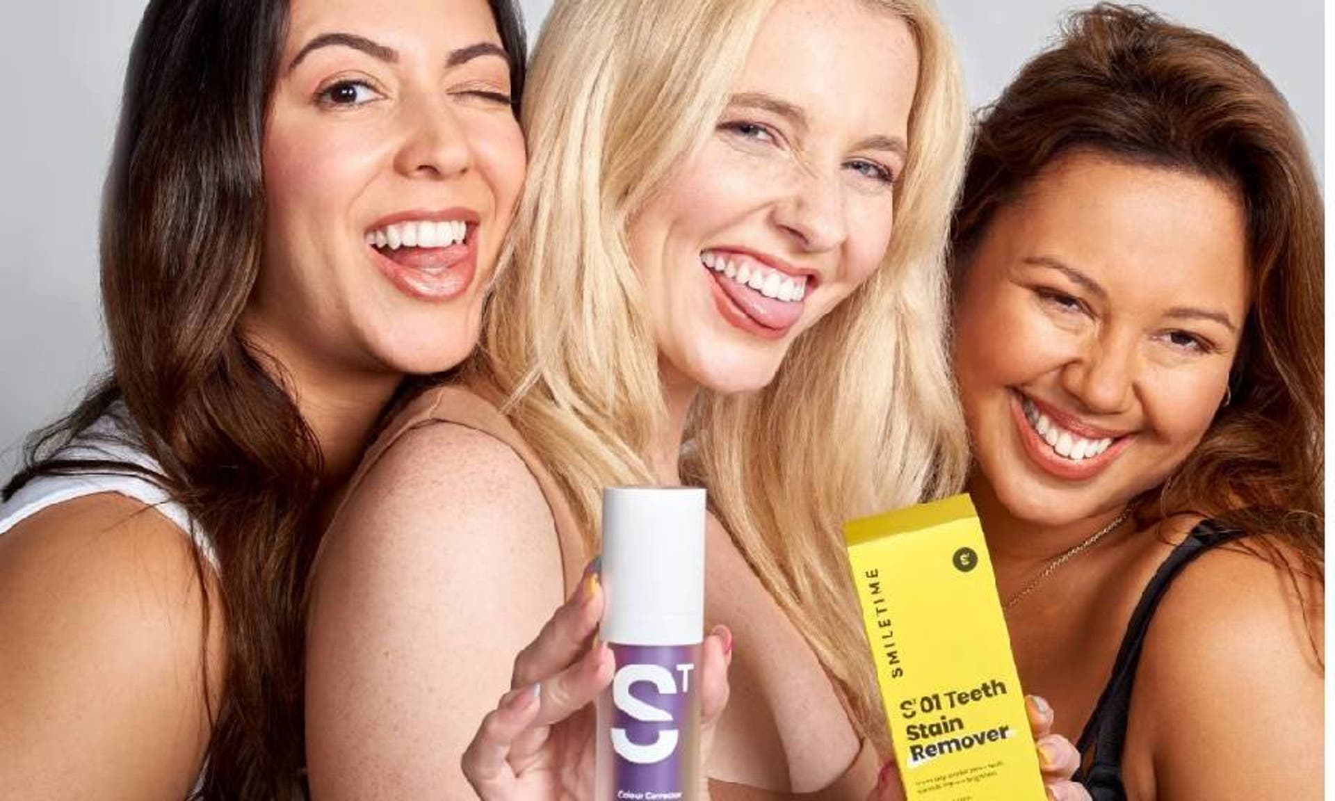 Three women smiling with their teeth, holding stain remover from Smile Time 