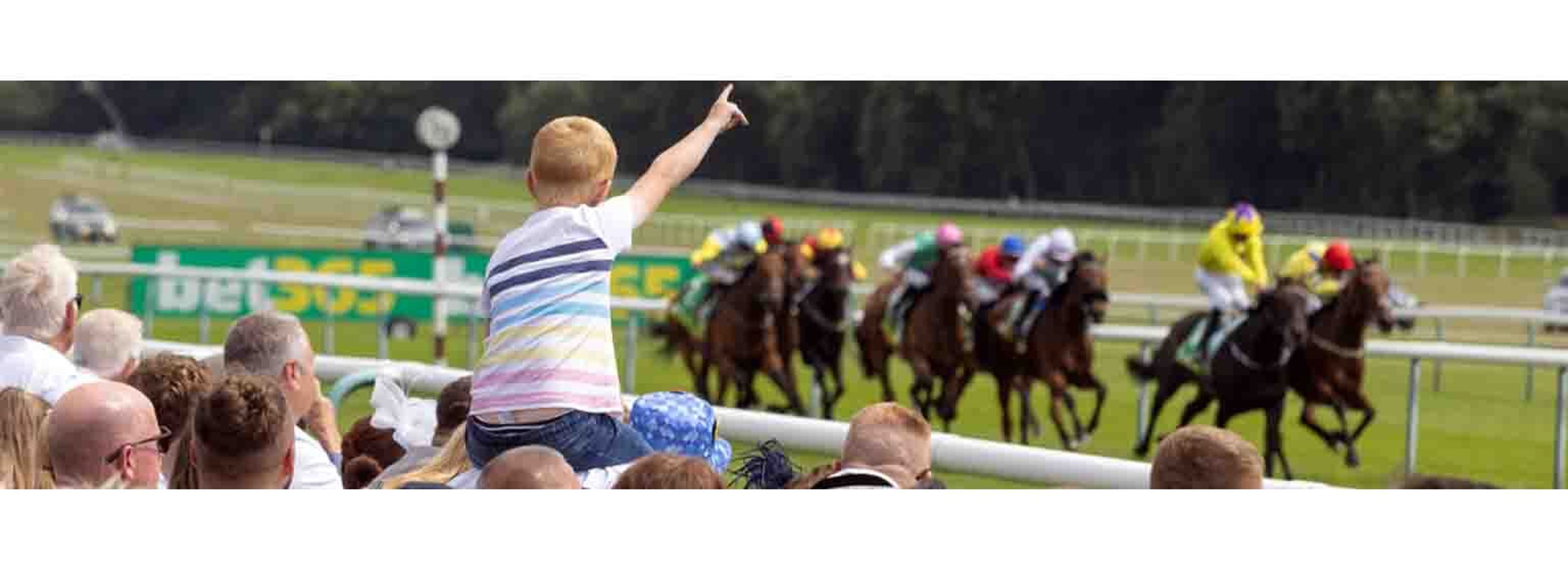 a little boy sitting on fathers shoulders pointing up looking at the races