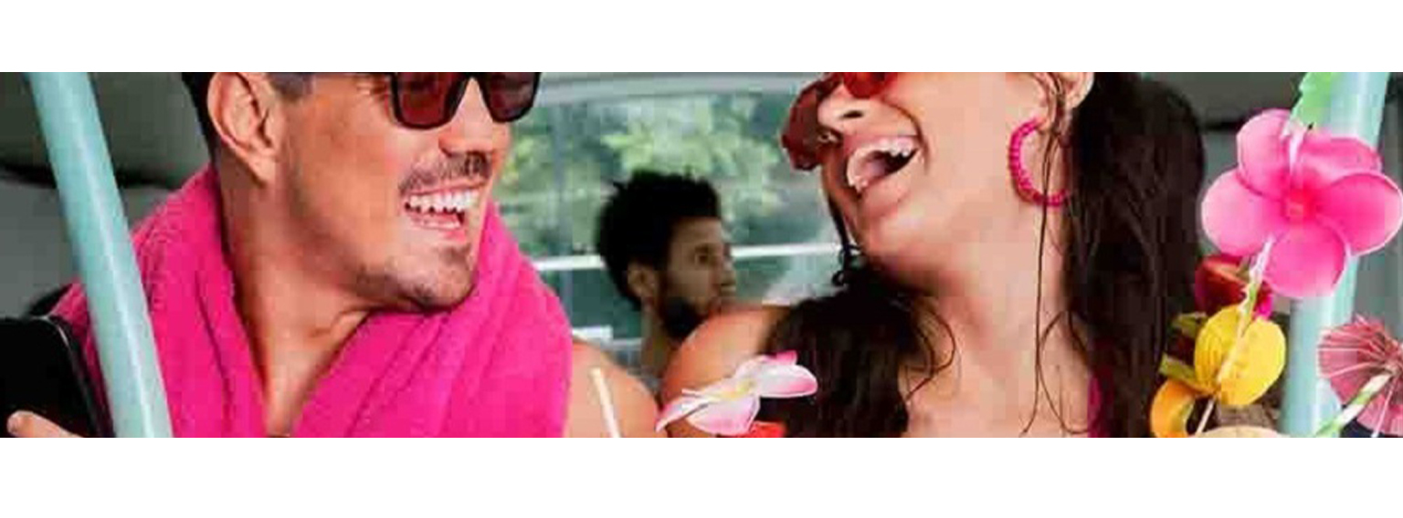  Boyfriend and Girlfriend on vacation wearing tropical clothes drinking from coconuts laughing at each other and enjoying each others company 