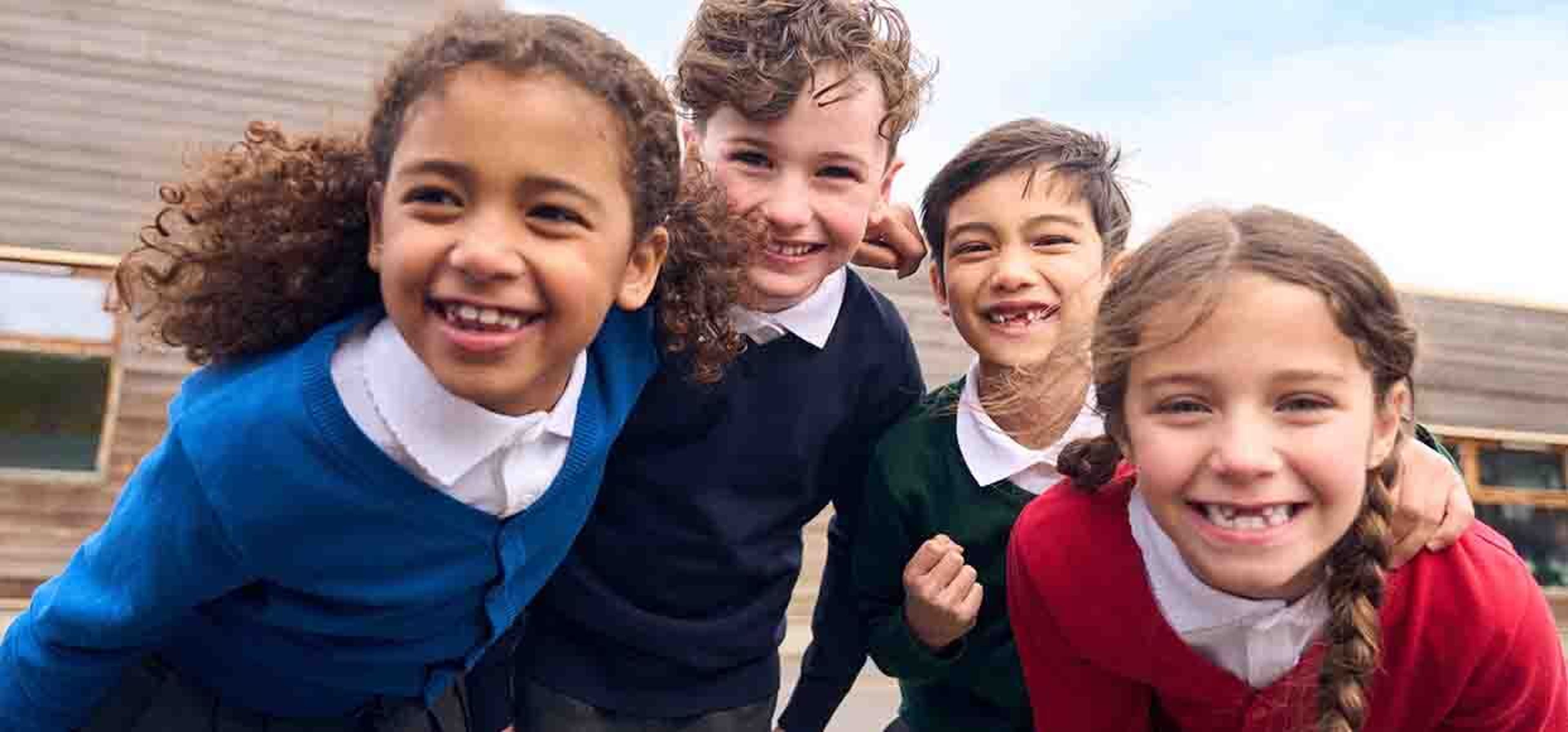 bunch of kids smiling closely at the camera in their uniform
