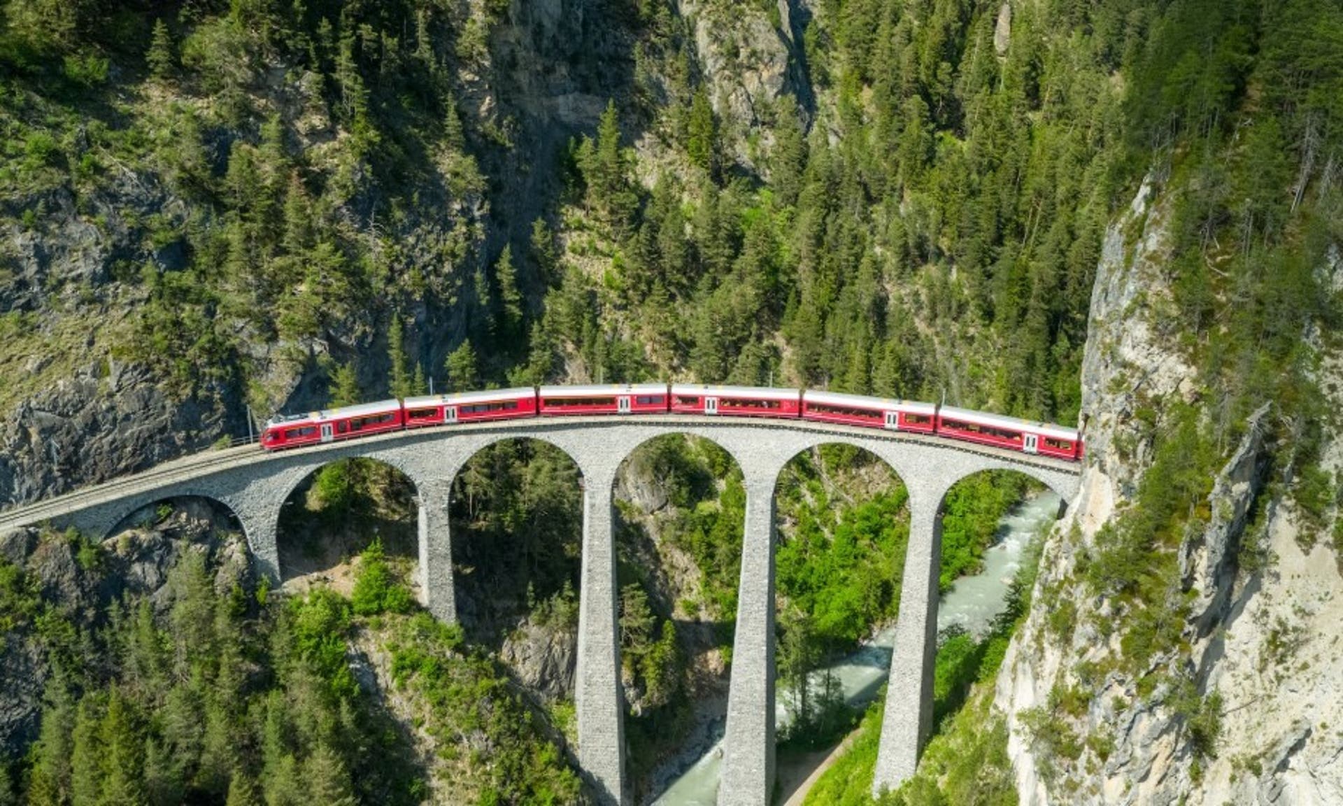  aerial shot of a train travelling along a scenic route in Switzerland 