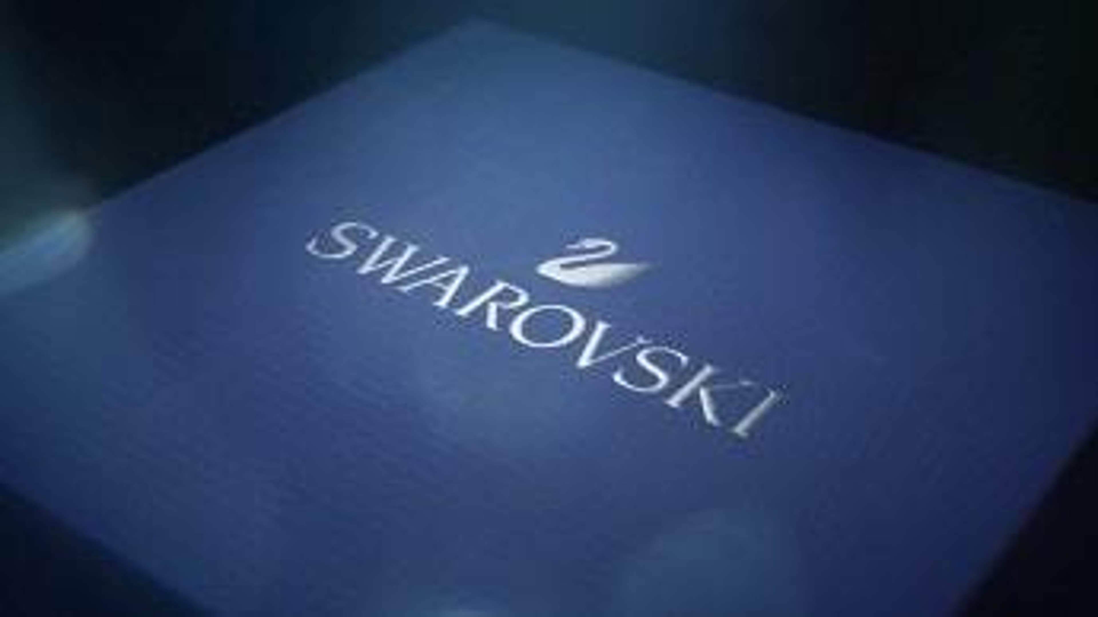  The Swarovski name & signature swan logo atop a blue gift box 