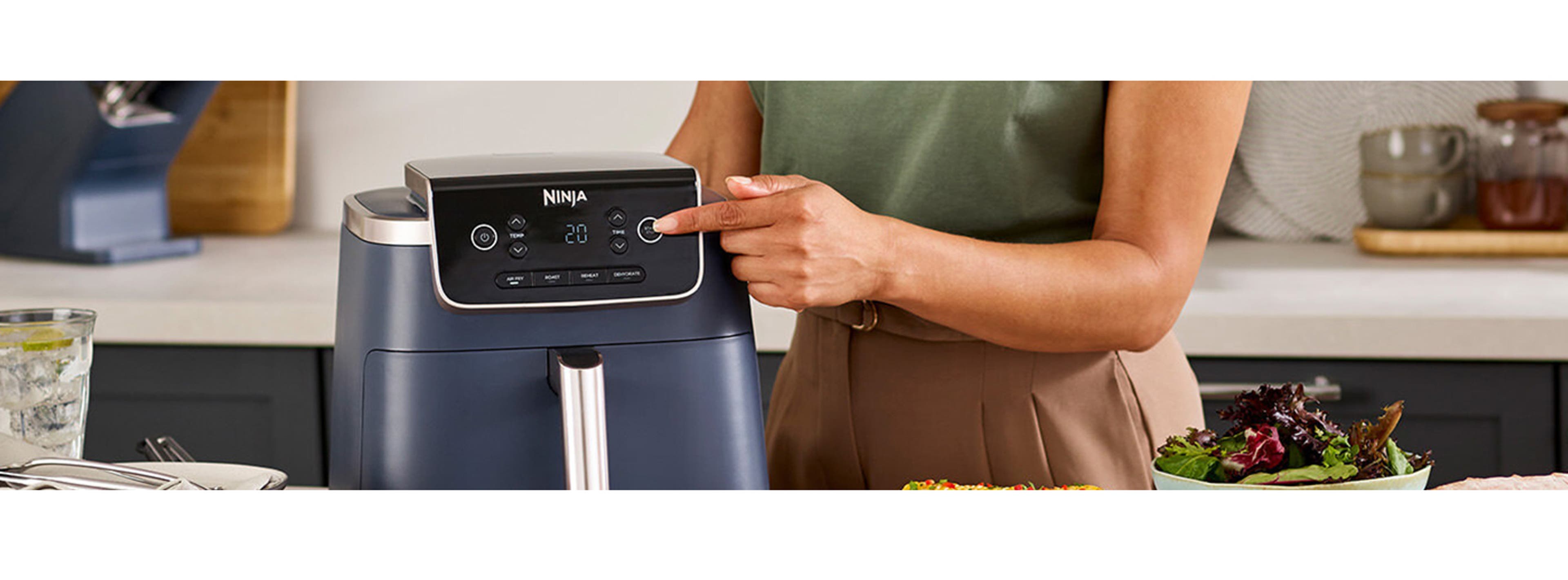 woman pressing a button on the ninja aryfryer machine