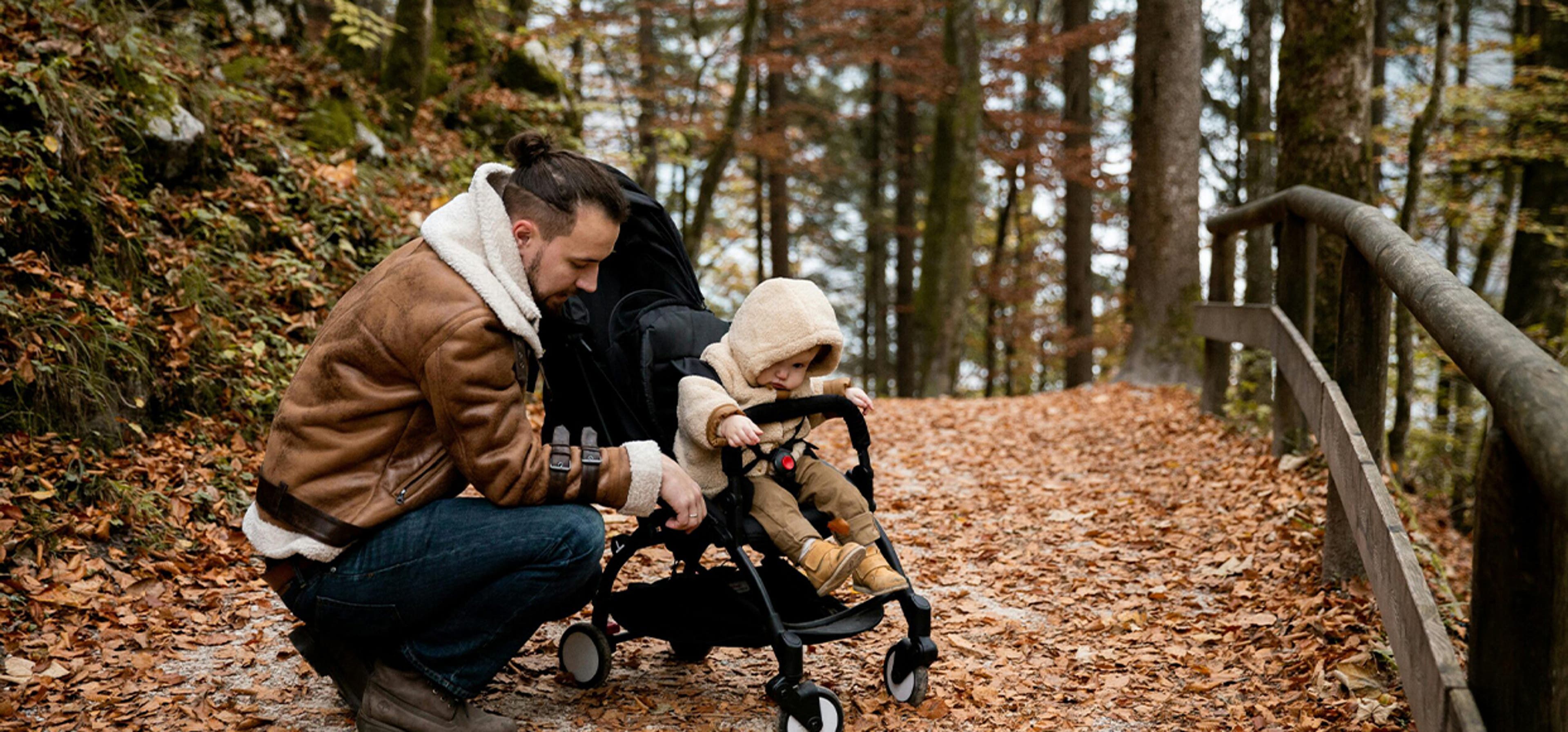 dad and baby in stroller in an autumn forest
