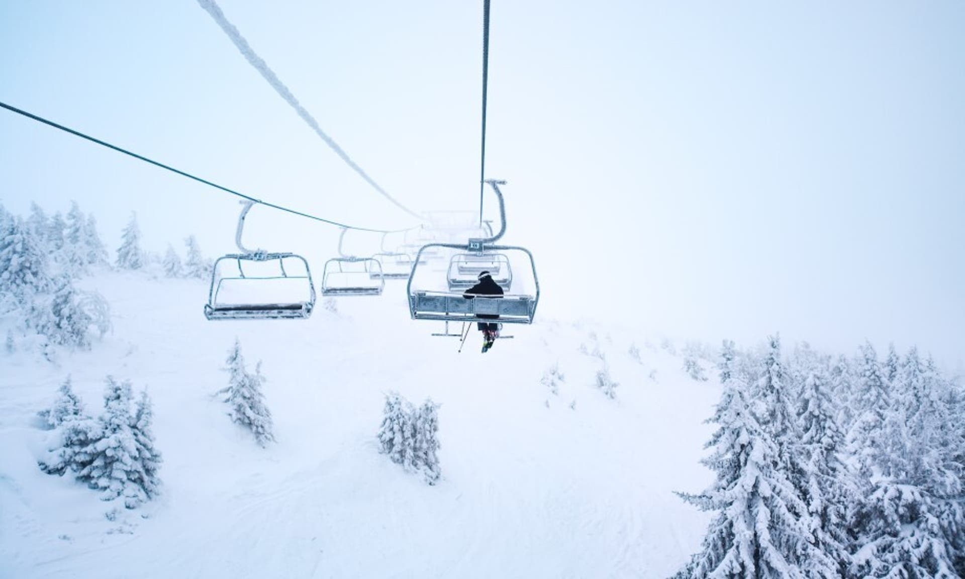  image of someone on a skilift, travelling up a snowy mountain 