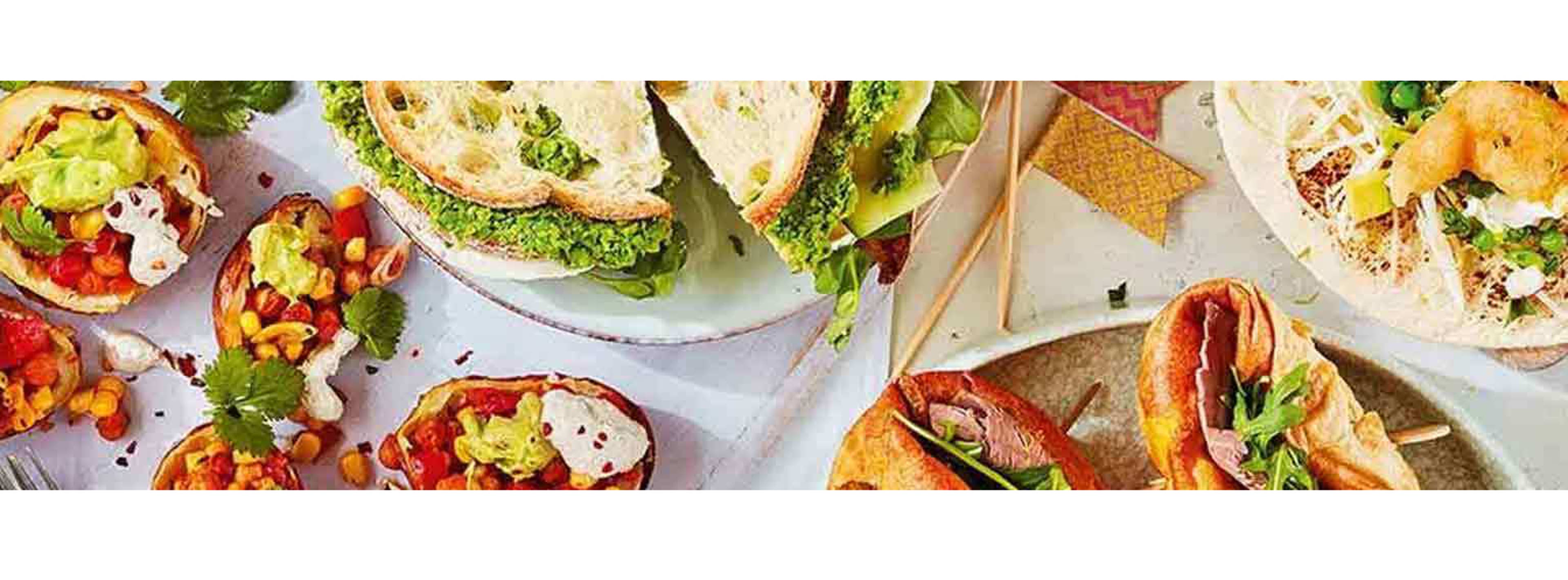 Image clicked from above of a table of food including different sandwiches