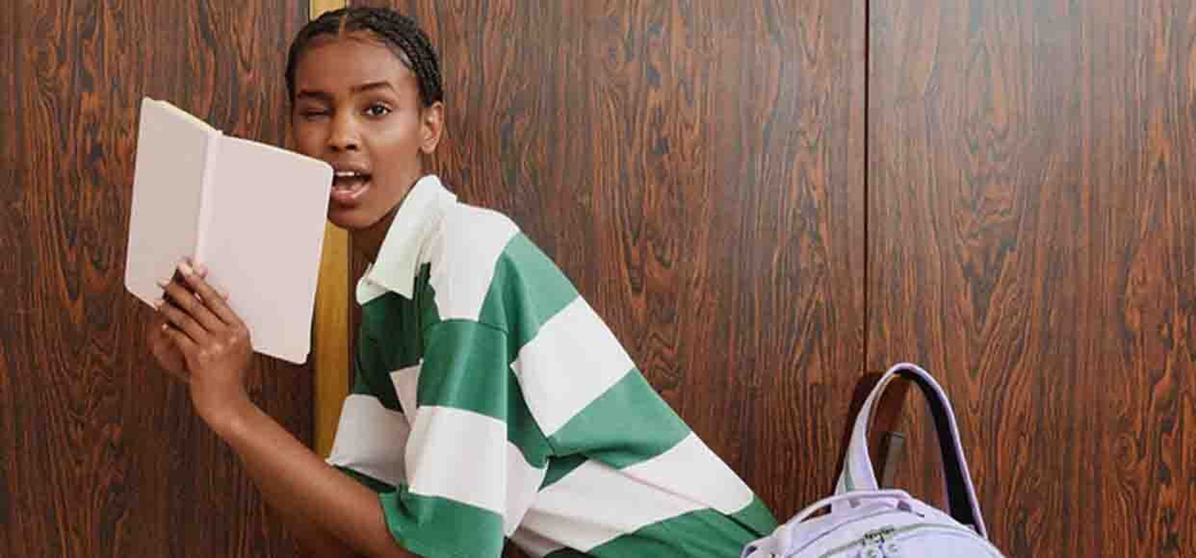 kid posing in striped shirt with book in hand and winking