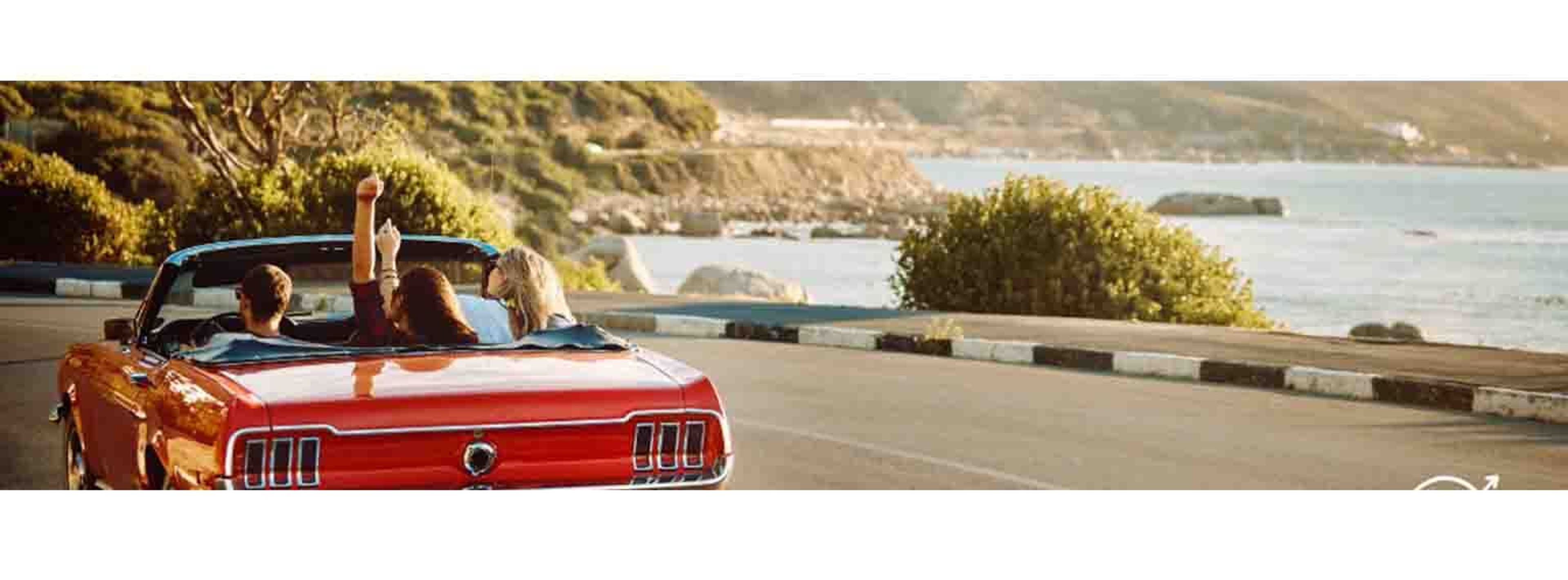 people in a red car driving on a windy road