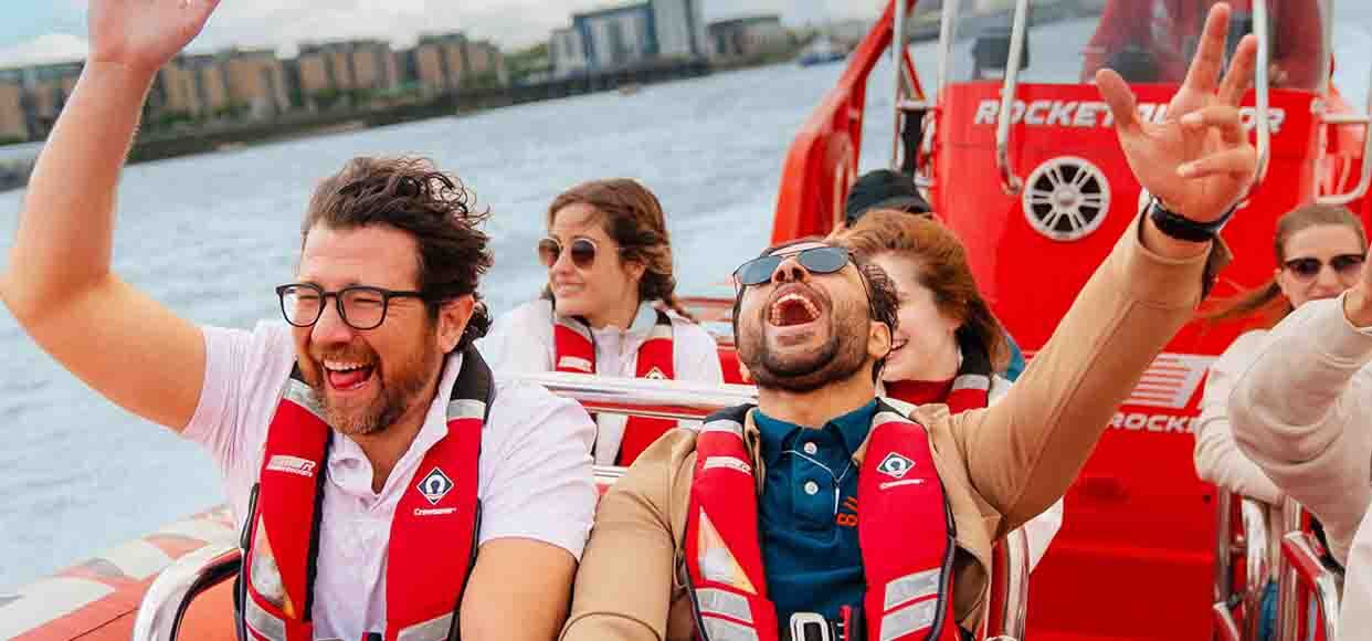  two people in life jackets on a speed boat, smiling happy  