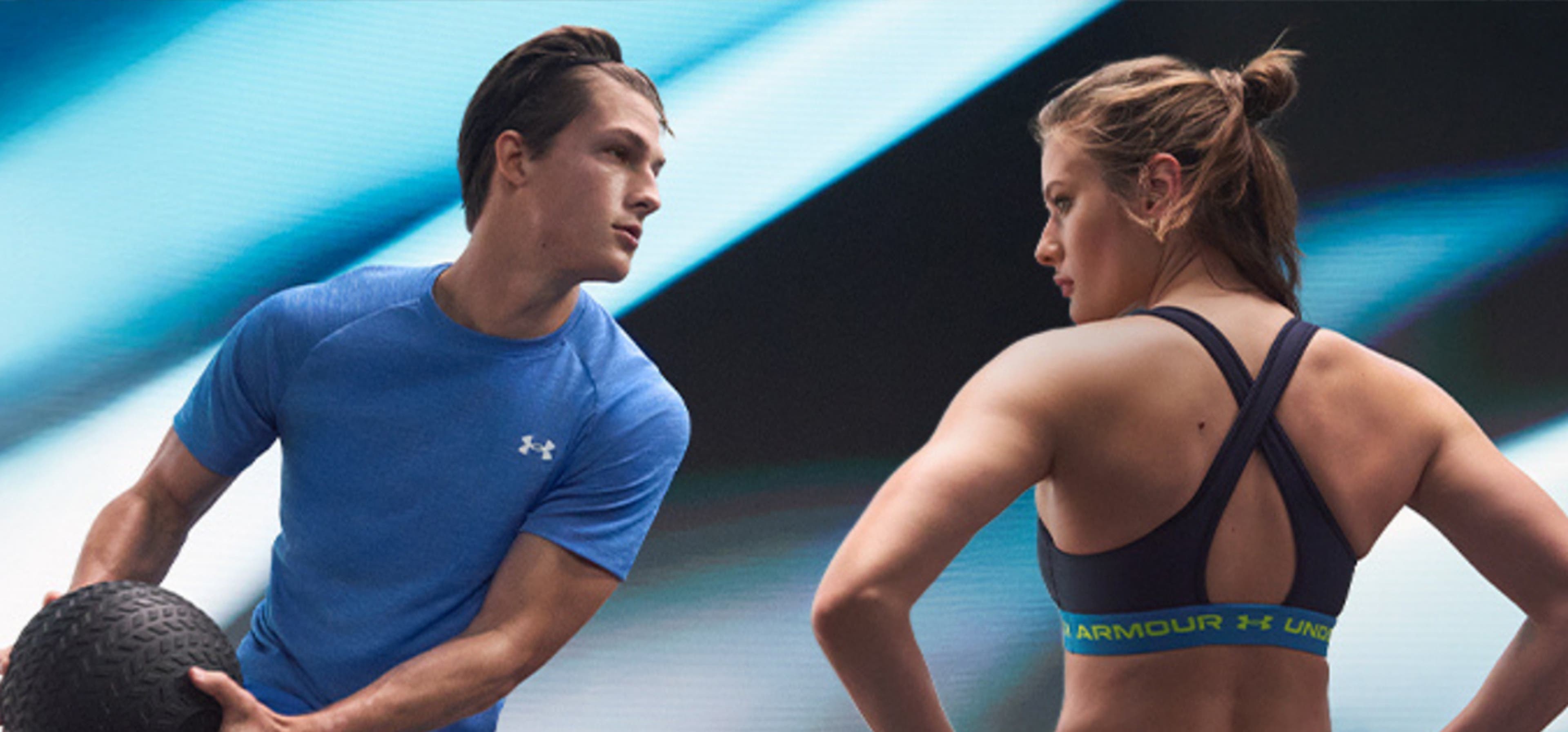 Man and Woman modelling Under Armour's athleisure wear with the man wearing a blue tshirt holding a ball and the woman wearing the brand's sport's bra