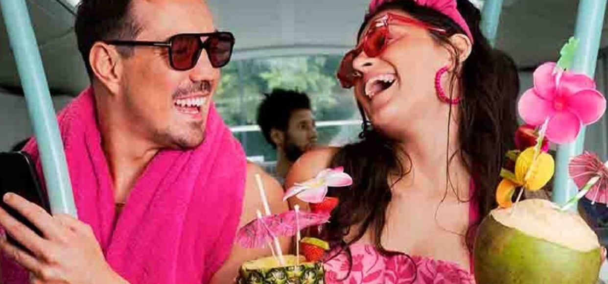  Boyfriend and Girlfriend on vacation wearing tropical clothes drinking from coconuts laughing at each other and enjoying each others company 