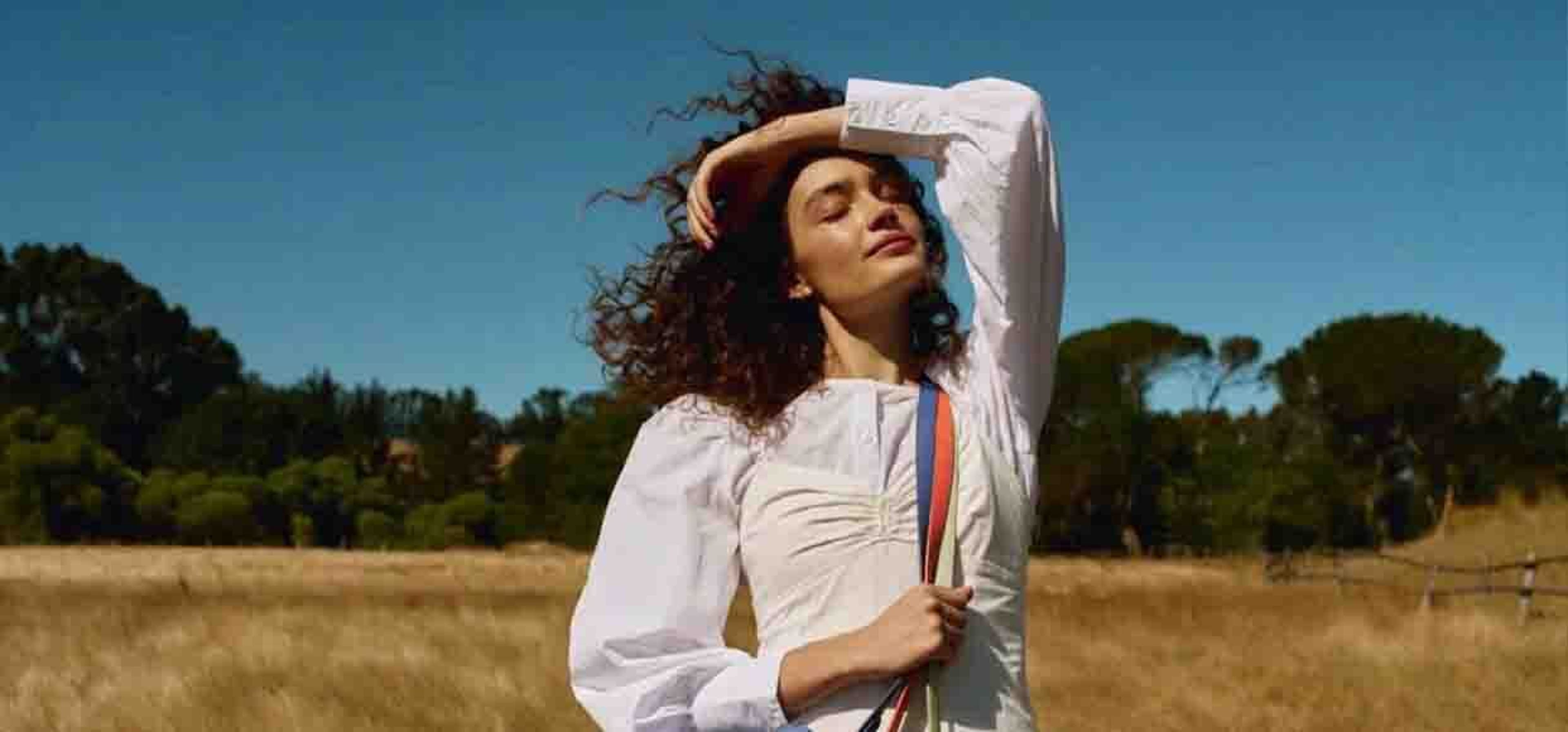 woman posing in a field with multiple bags