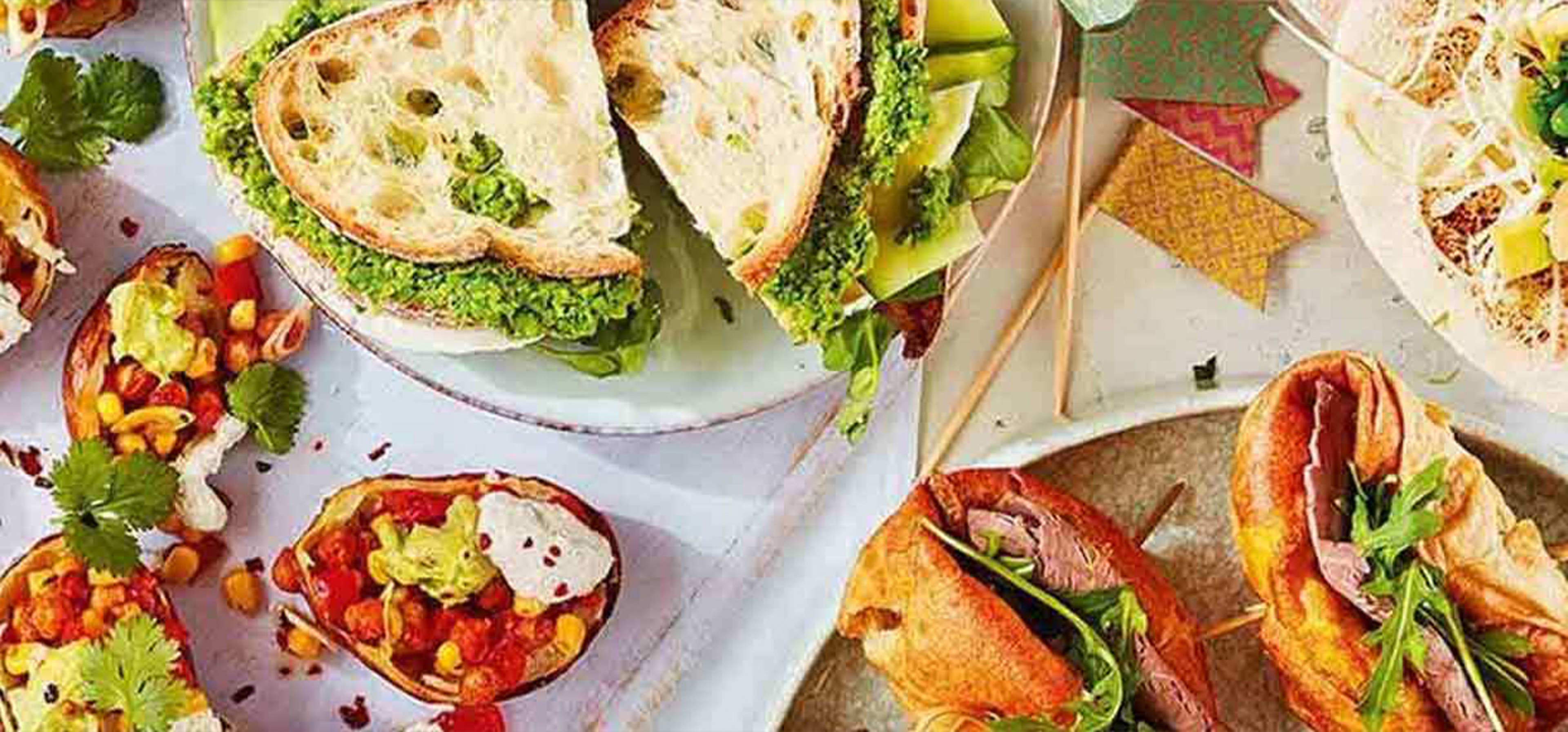 Image clicked from above of a table of food including different sandwiches