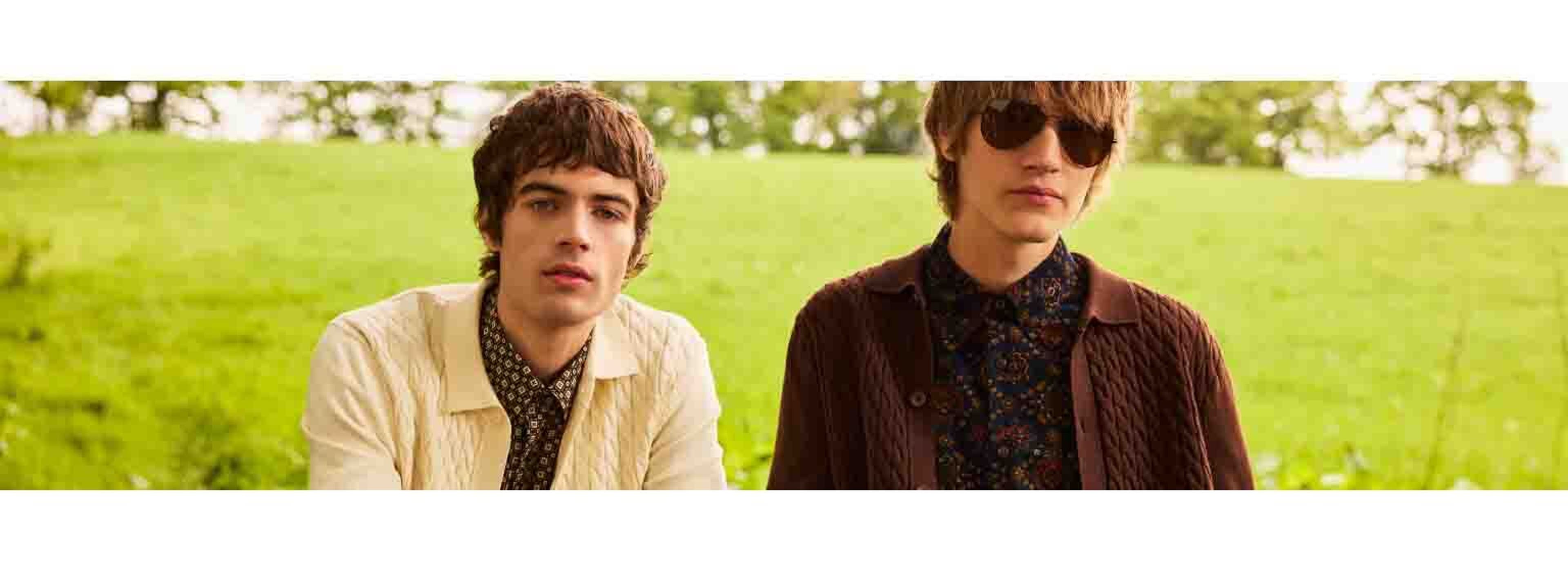 Two boys with long haircuts posing in a field