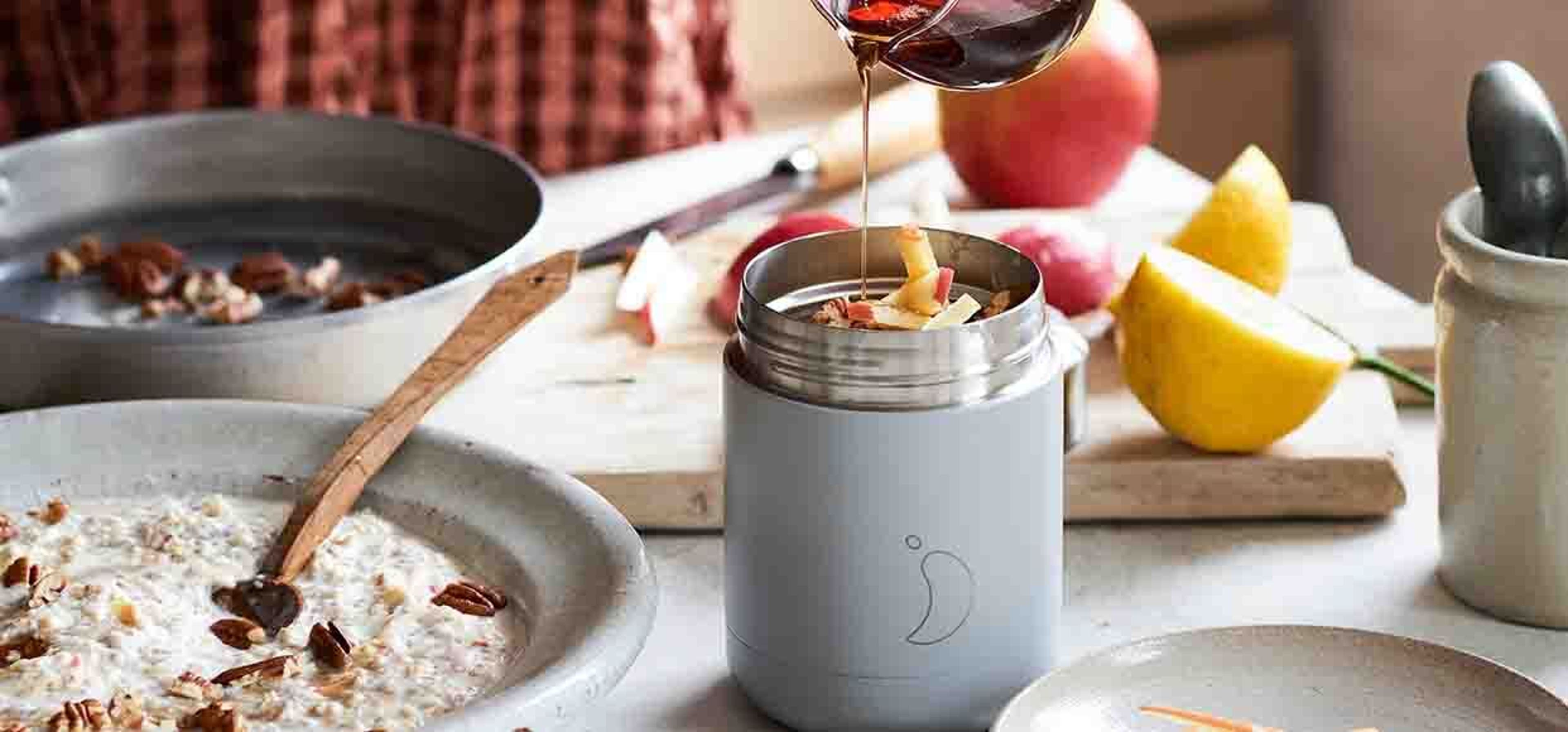 person pouring honey in a foot pot filled with apples