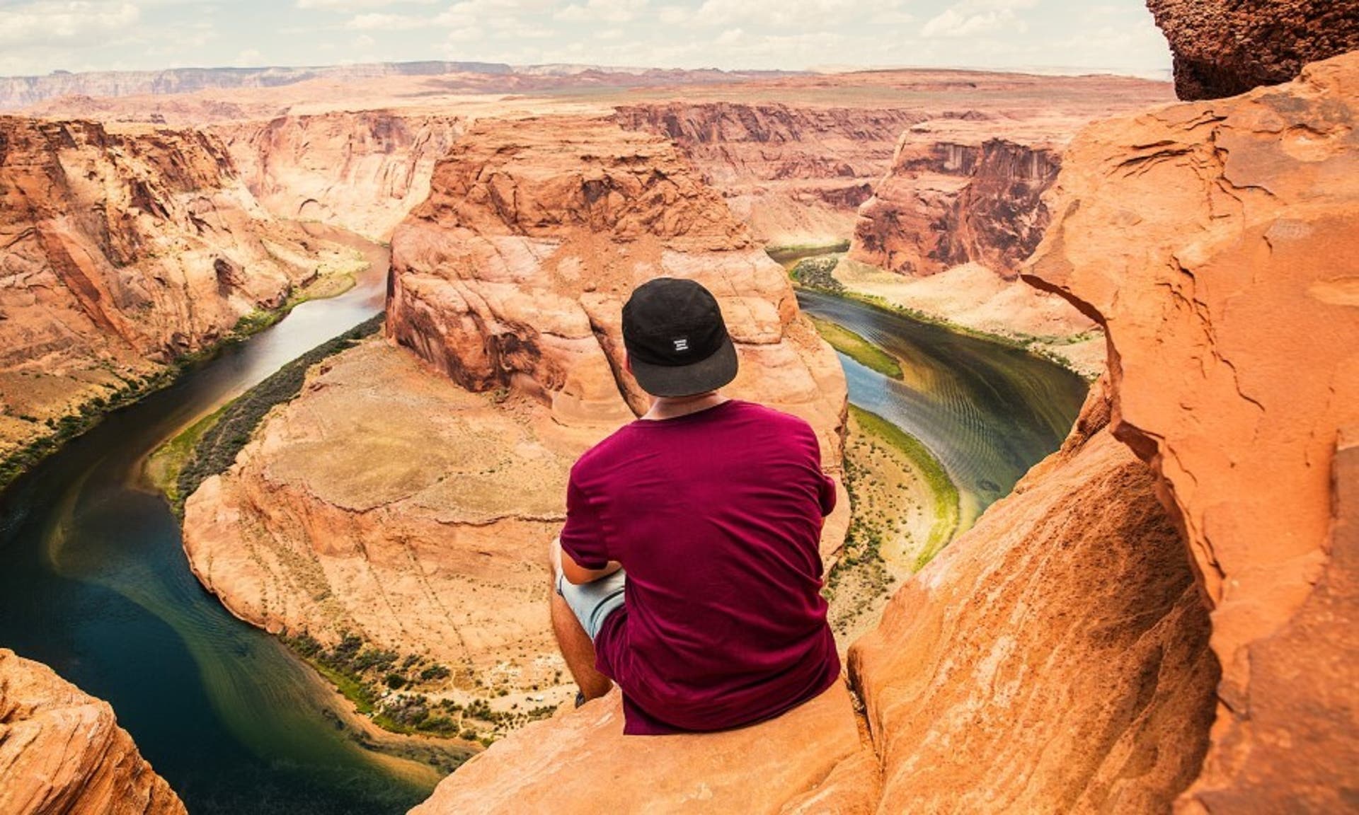  man sat on the edge of a canyon looking out at the views 