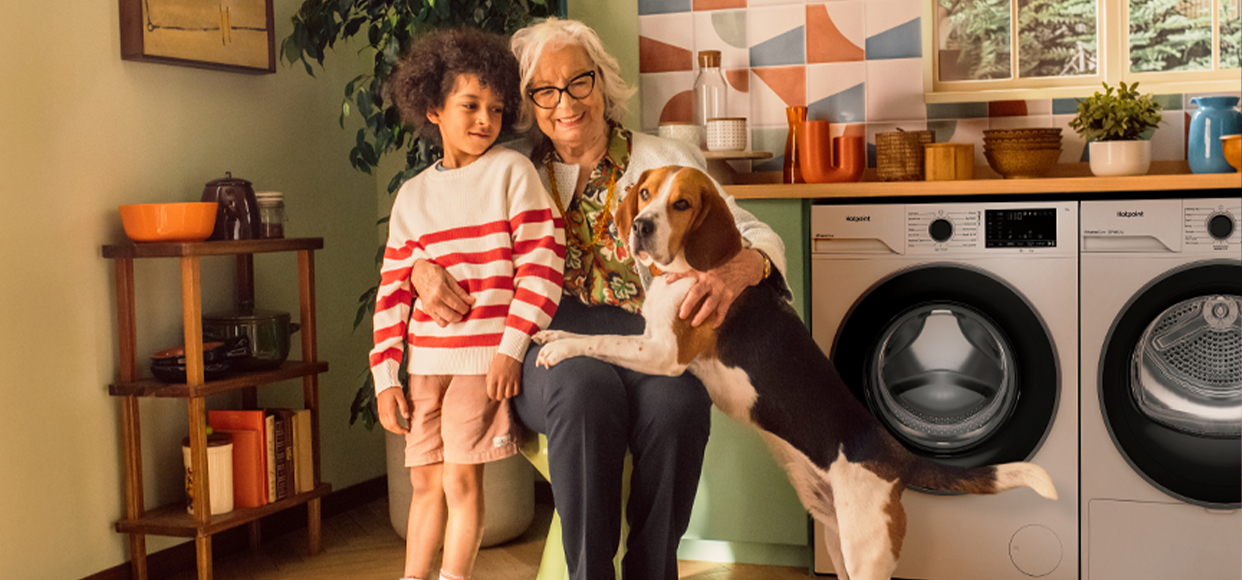  Grandmother hugging her grandson and dog in the kitchen 