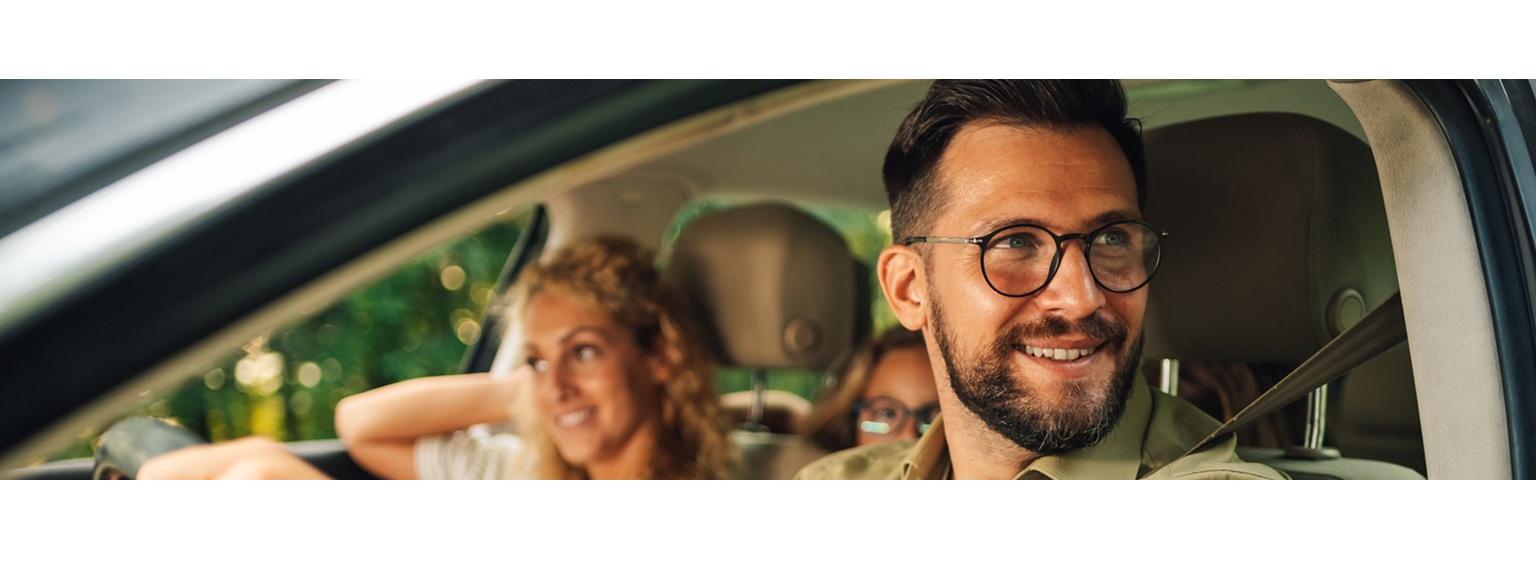  Dad driving car with mom in passenger seat and kids in the backseat during their vacation 