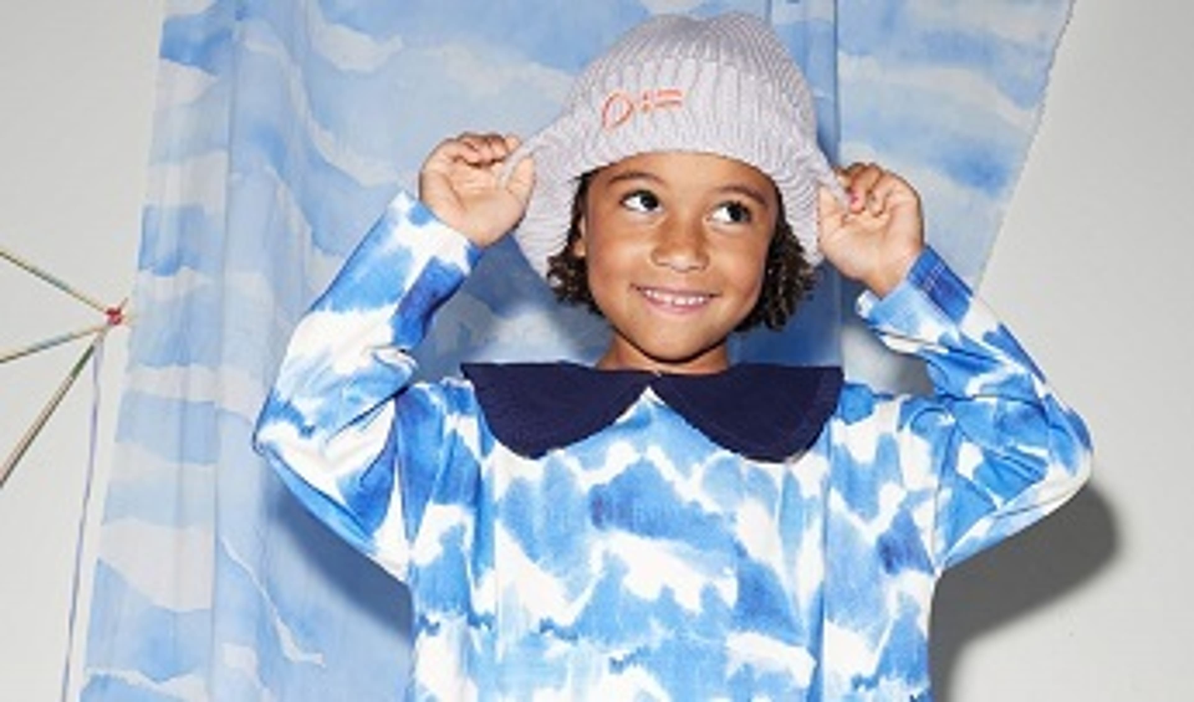  A child wearing a white hat and patterned blue dress from Alex and Alexa 